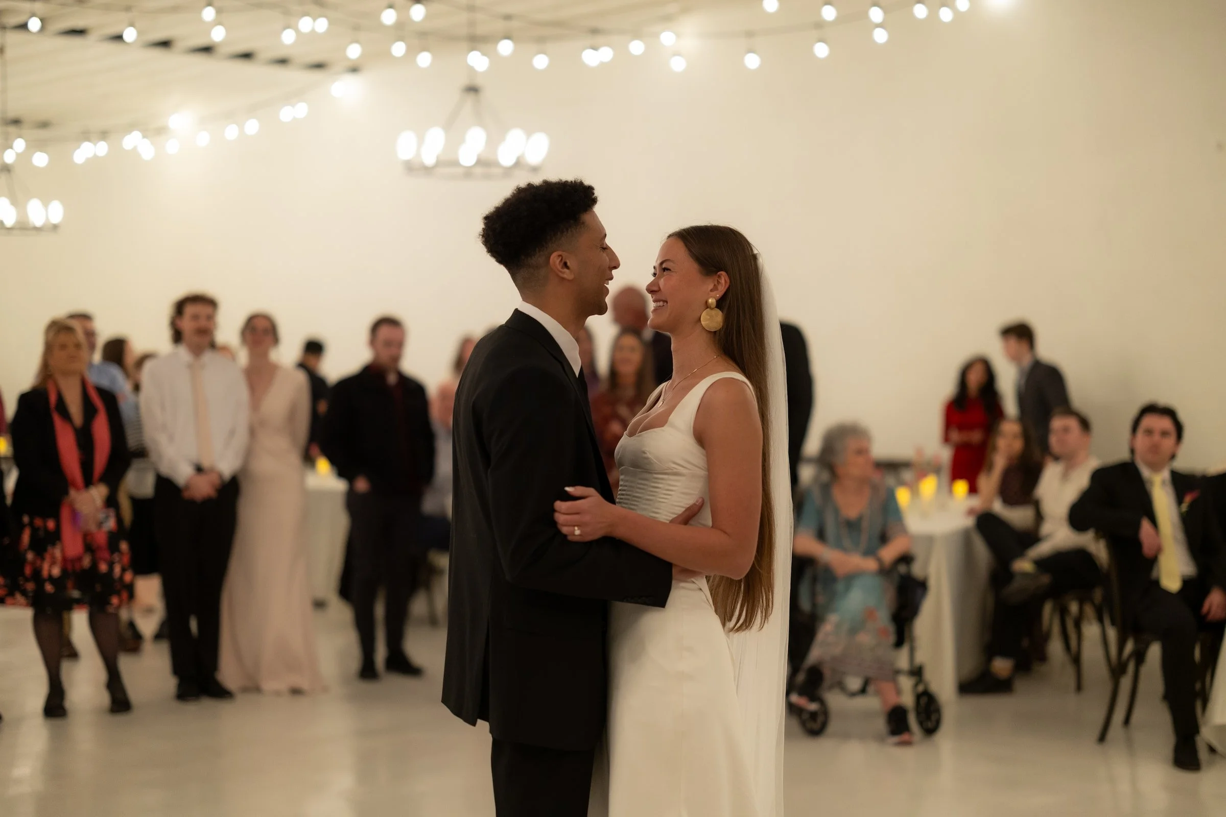 couple-first-dance-guests-watching-string-lights-the-ivory-hall-provo-utah.jpg