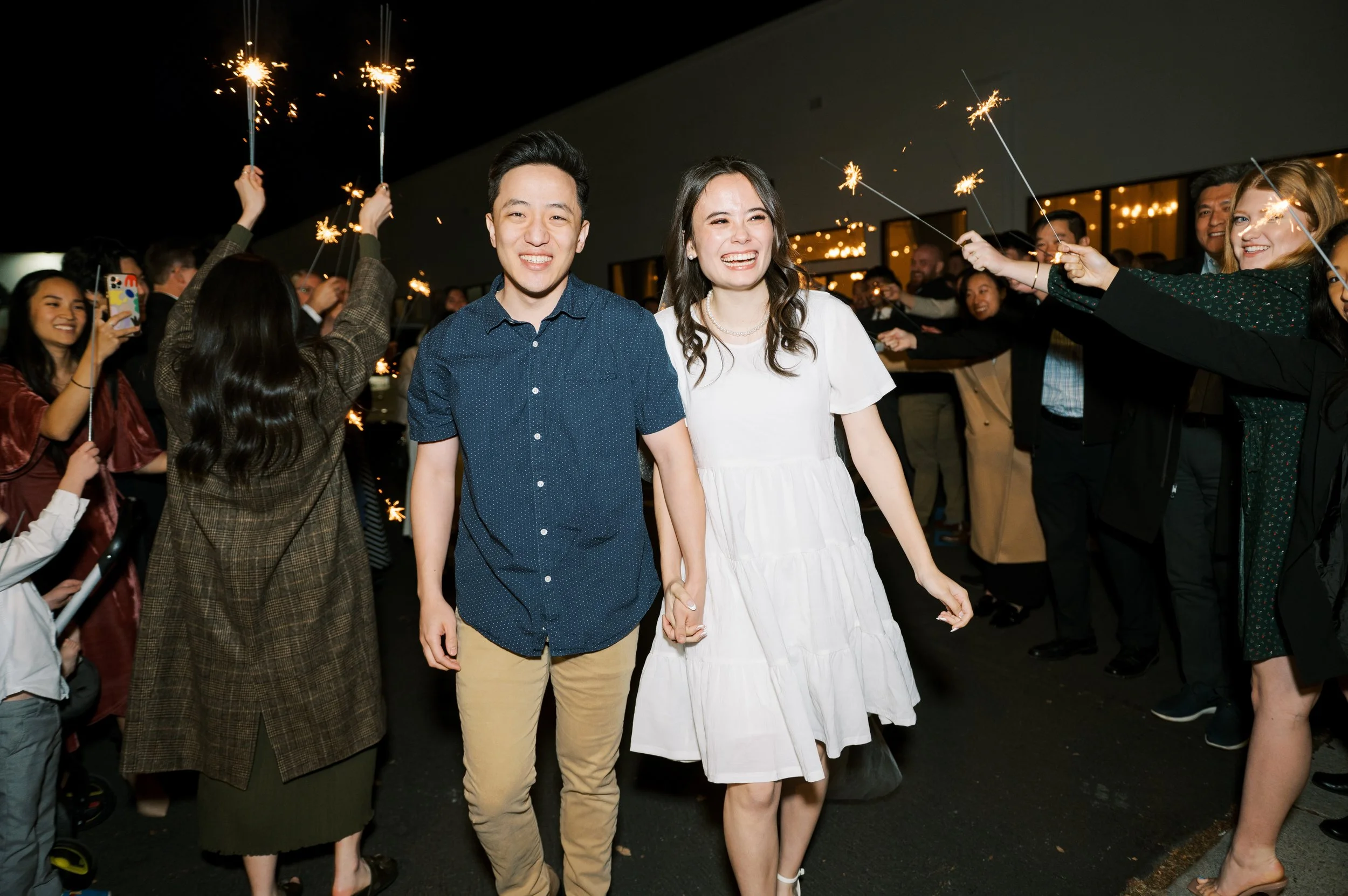 Couple walks hand in hand beneath a canopy of sparklers outside The Ivory Hall, highlighting a fun and magical wedding grand exit moment.