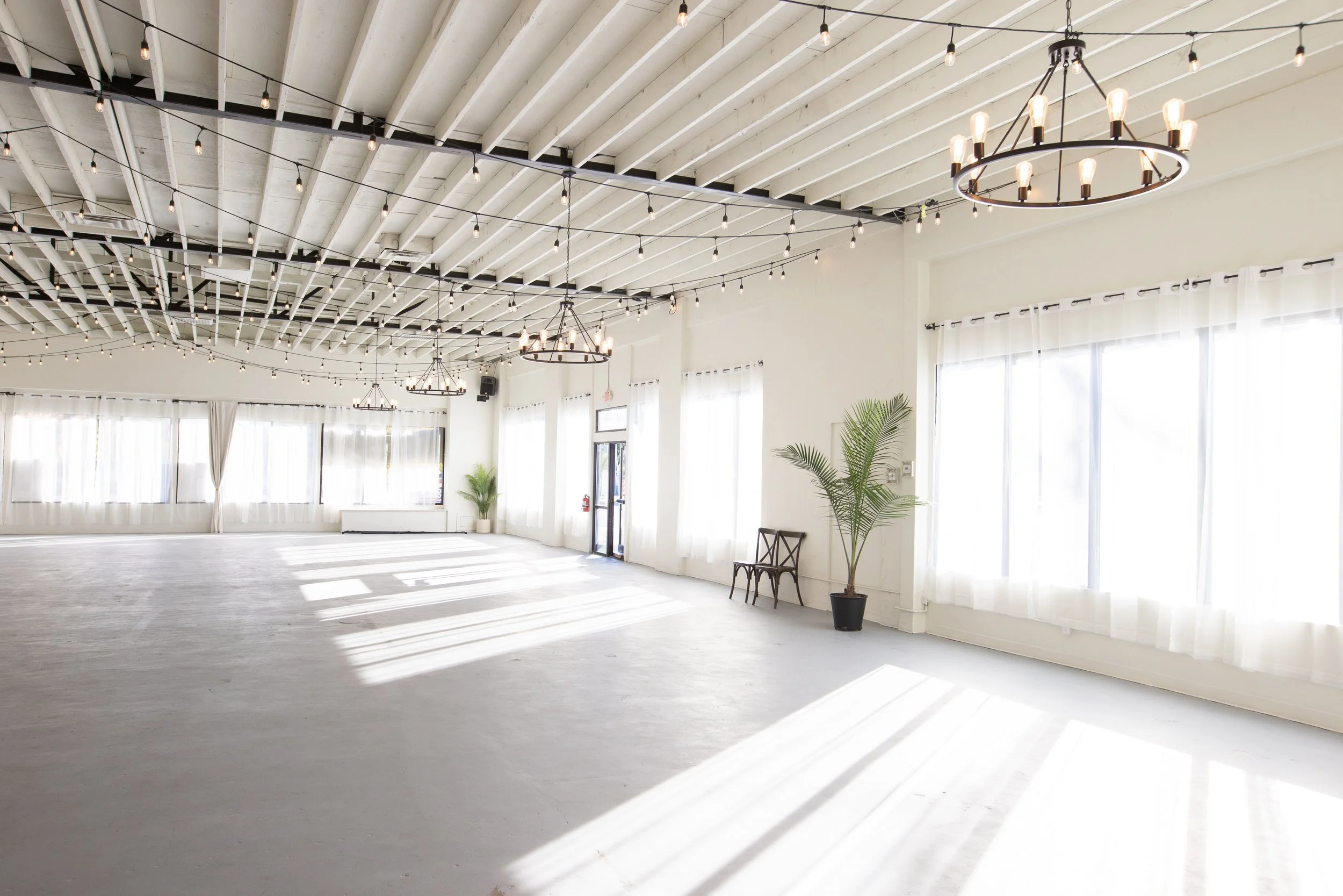 Sunlit event space with curtains and chandeliers

Another angle of The Ivory Hall’s open area, showcasing long flowing curtains and overhead chandeliers bathed in afternoon light.

