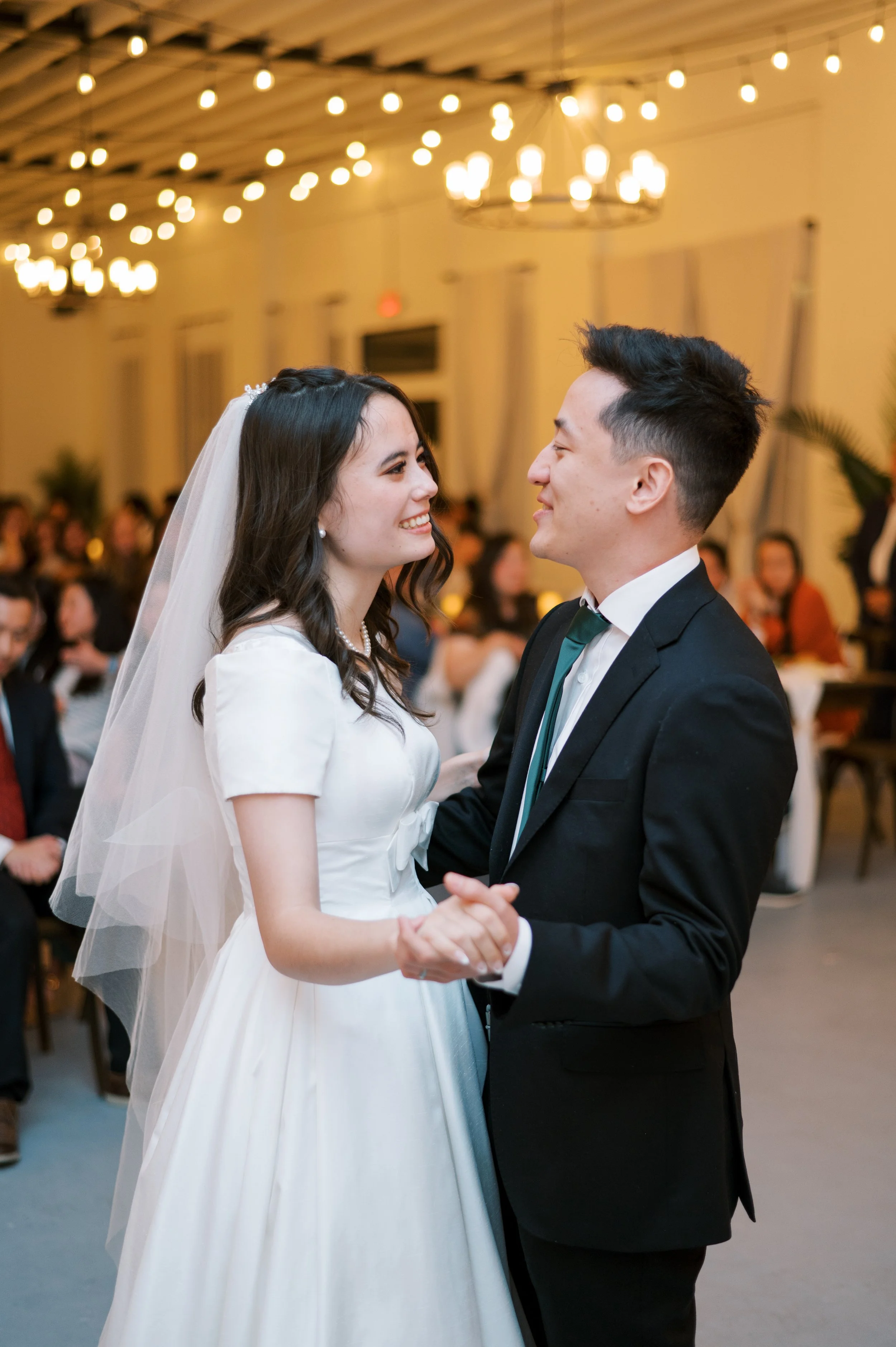 Bride and groom share their first dance at The Ivory Hall, surrounded by friends and family in a warmly lit, intimate wedding celebration.