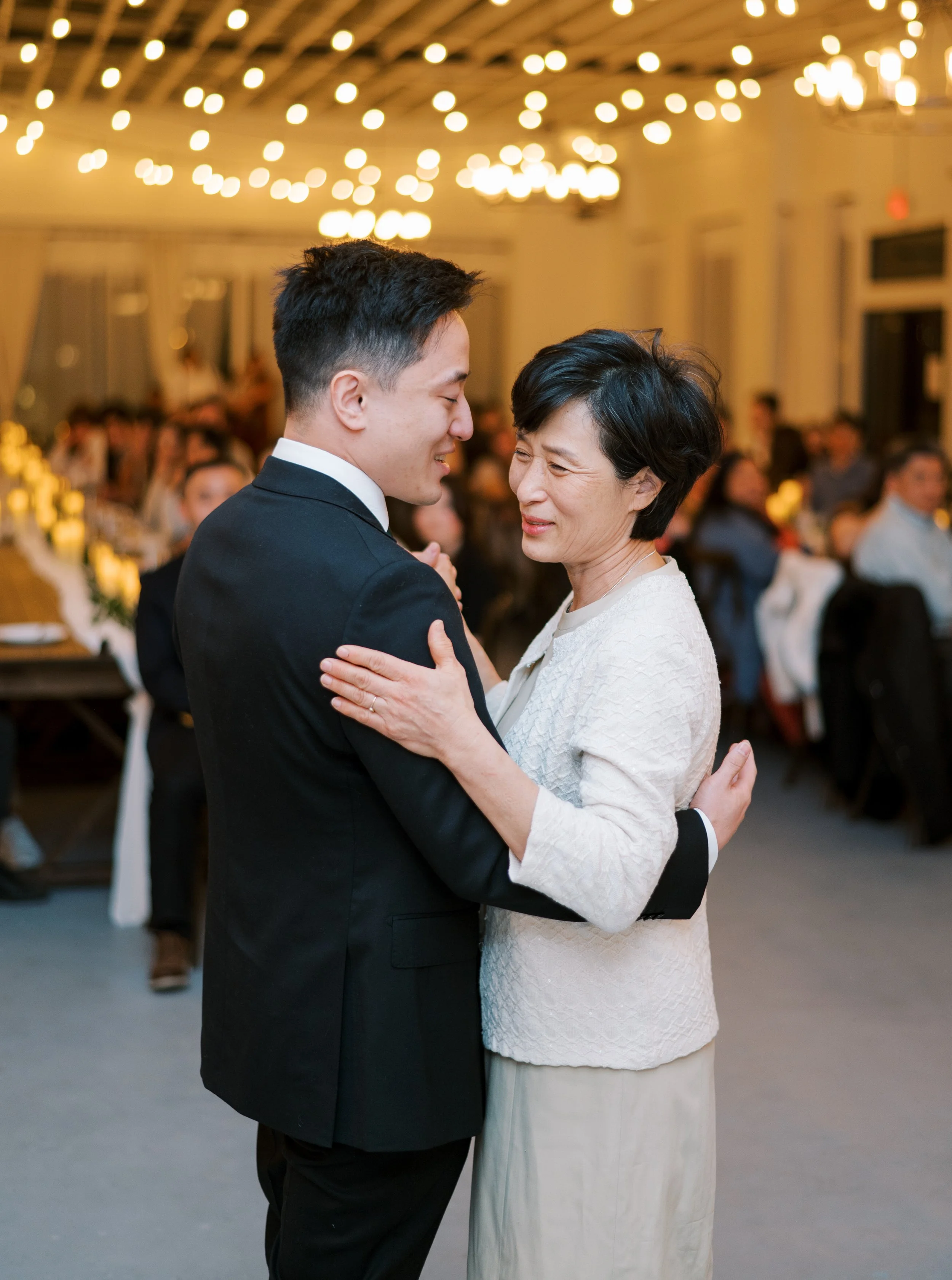Mother-son dance during a wedding reception at The Ivory Hall, capturing a heartfelt moment under romantic chandeliers and glowing lights.