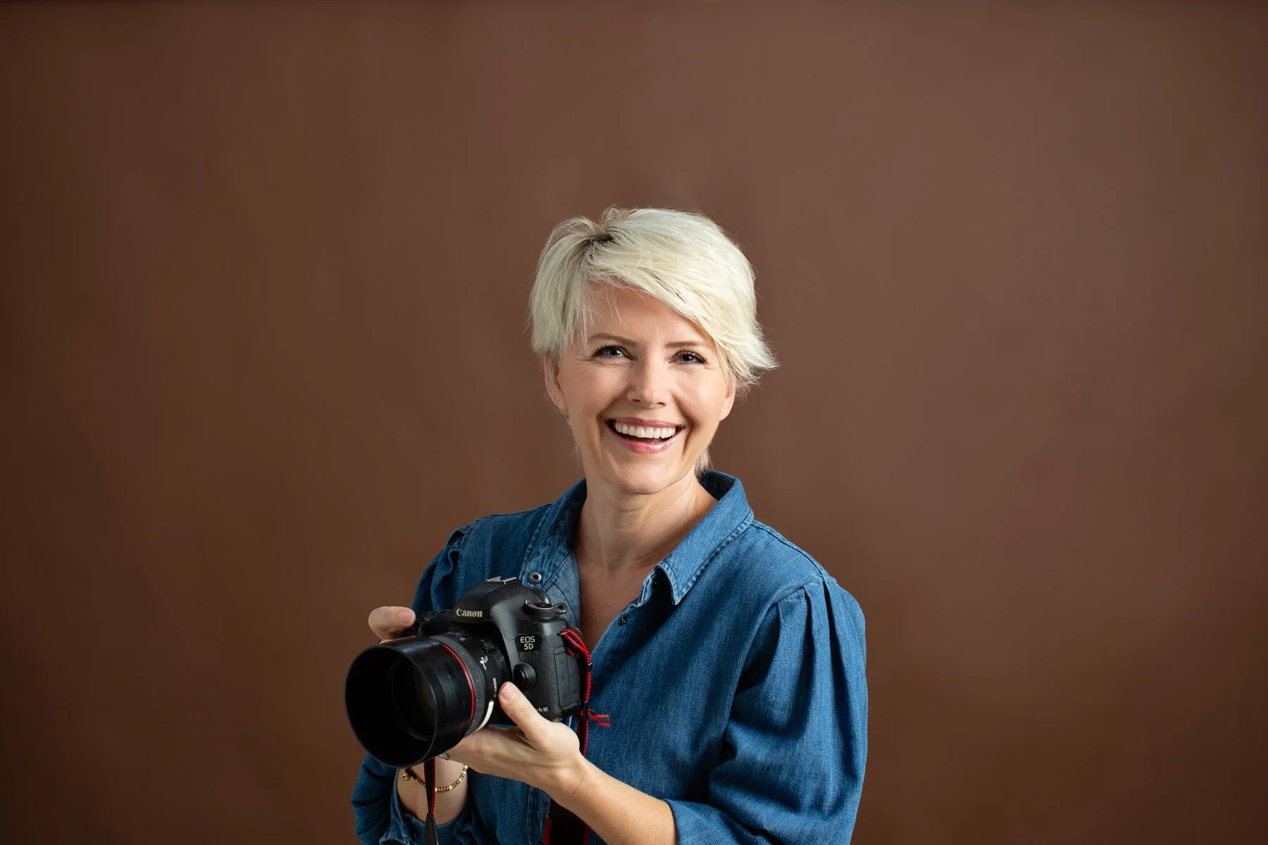 Simona Janek, photographer, wearing a denim top and smiling confidently, ready for maternity photography sessions.