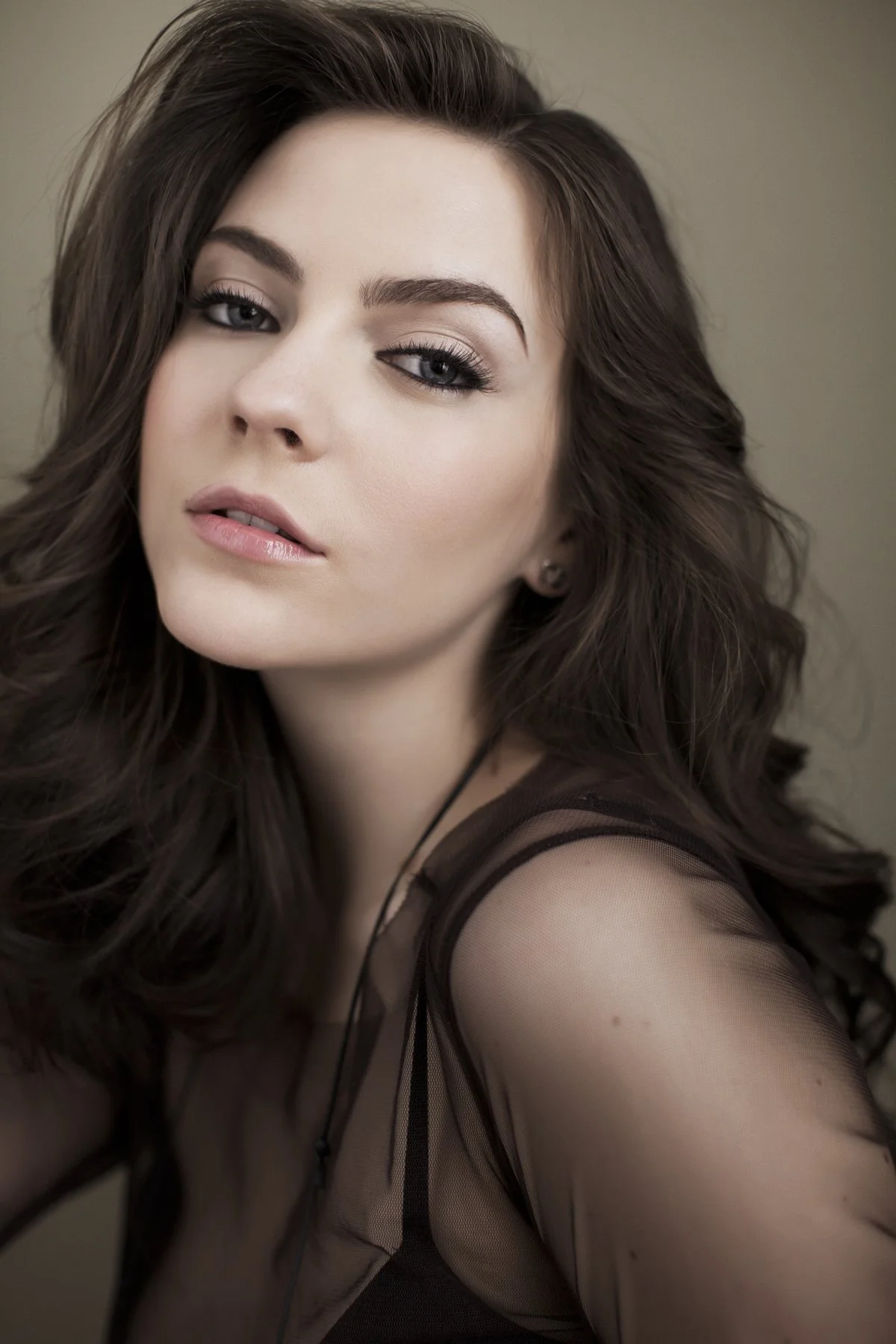 Close-up glamour portrait of a woman with dramatic eye makeup and voluminous brunette hair — professional beauty photography