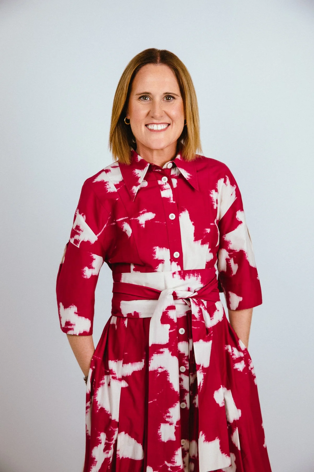 Professional portrait of a smiling woman wearing a bold red and white patterned dress, demonstrating how colour and patterns can work for professional headshots.