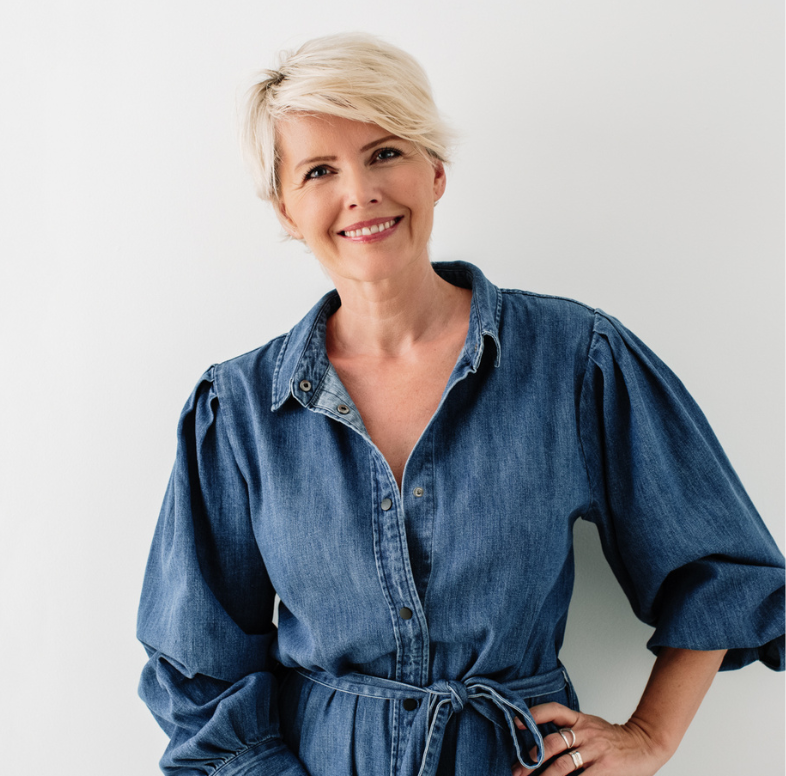 Simona Janek, photographer, wearing a denim dress and smiling confidently, ready for Makeup Masterclass sessions.