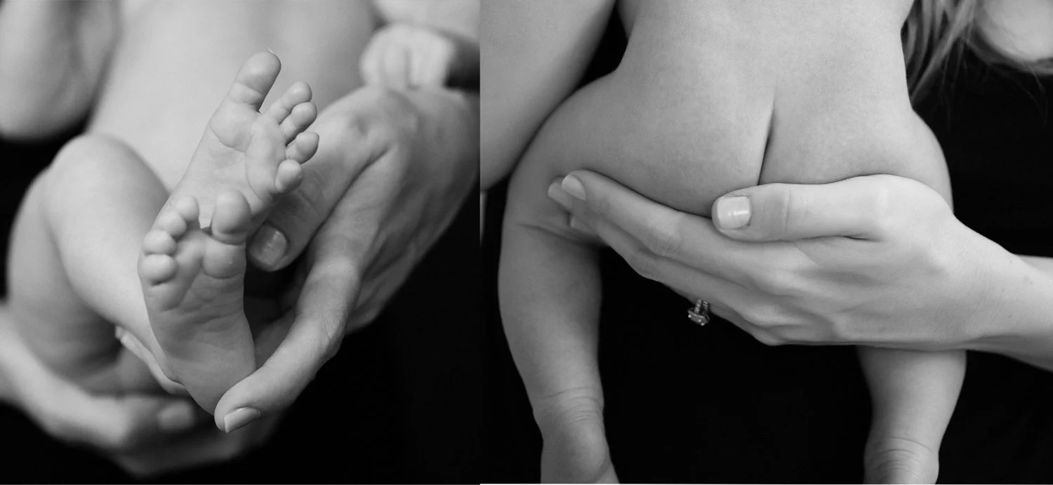 Black and white close-up newborn photography — tiny baby feet cradled in mother's hands
