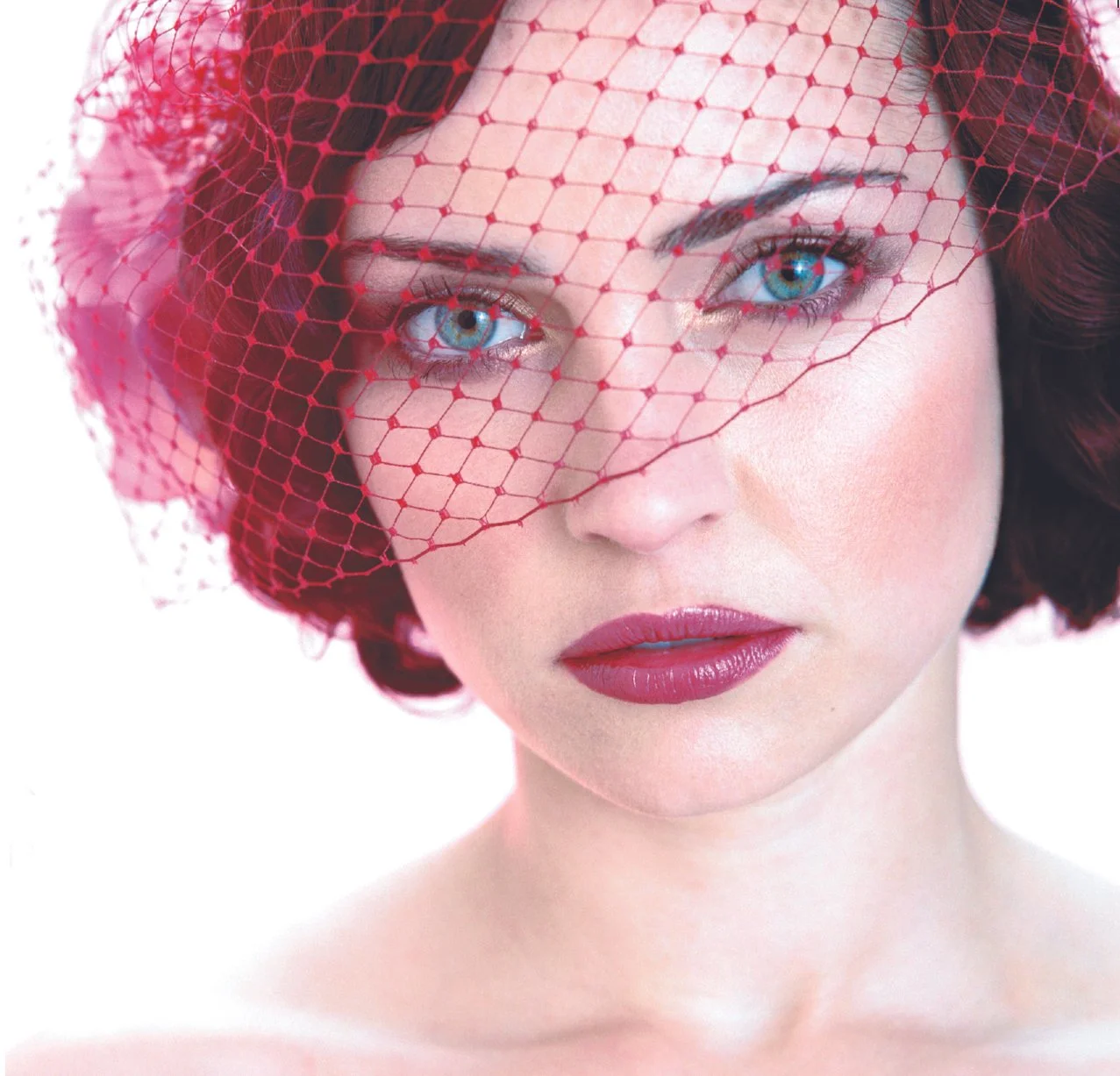 Bold editorial makeup look featuring deep berry lips and striking blue eyes behind a red veil — makeup lesson result by Simona Janek