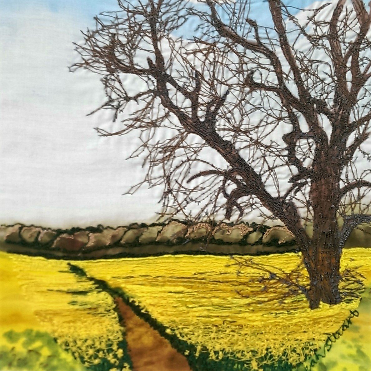 Freestyle Machine Embroidered rapeseed field with pathway and large tree.
