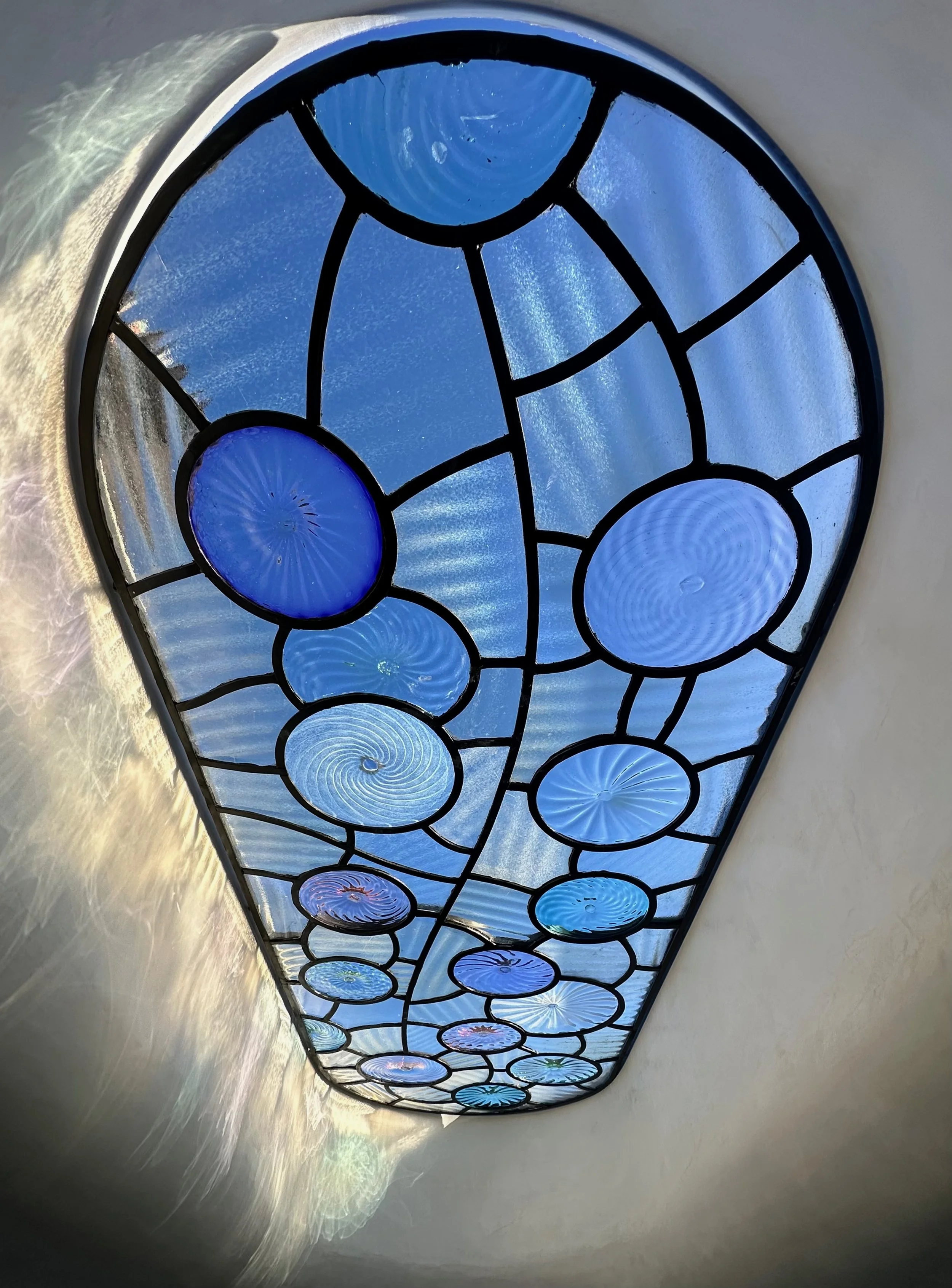 Sculptural residential skylight above a curved stairwell, designed and handmade by artist blacksmith David Wood of Bent Metal, with hand-blown glass by Billy Crellin.