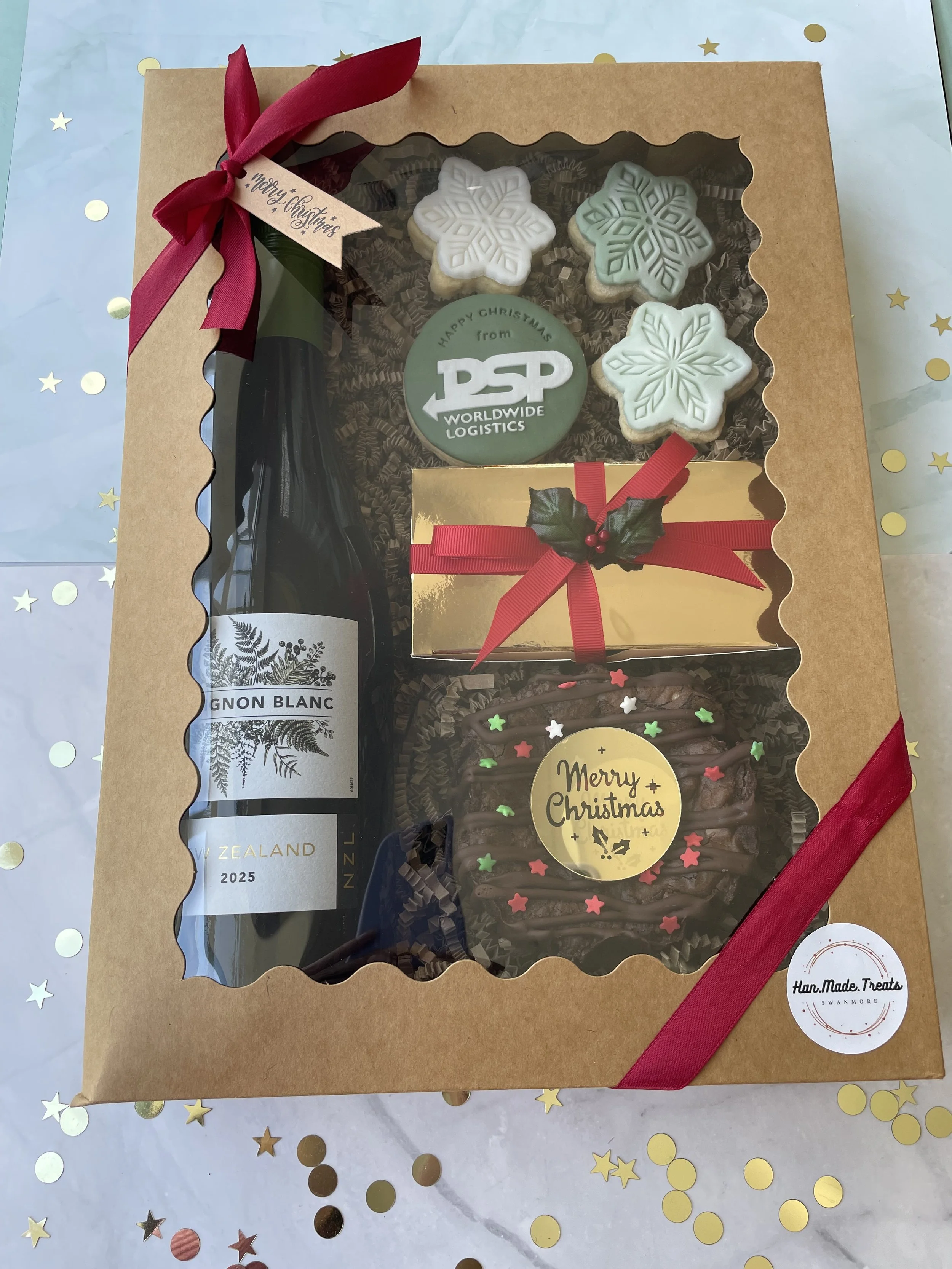 Large Hamper - £35.
Includes: Bottle of wine, a Triple Choc Brownie Round, ‘Happy Christmas from’ Logo Shortbread Biscuit, Mini snowflake biscuits & Box of Belgian Chocolates from Confiserie Verdonk.
