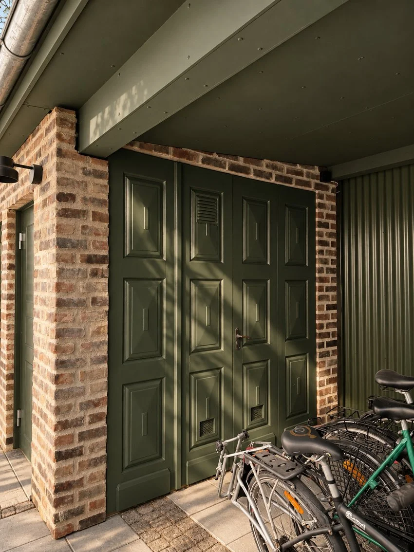 Förråd på gården av återbrukat tegel från skorstenar samt återbrukad garageport.