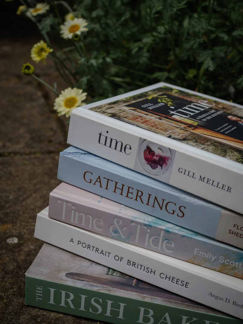 A stack of story-filled seasonal cookbooks photographed from an angle, reflecting slow living, food writing, and seasonal inspiration.