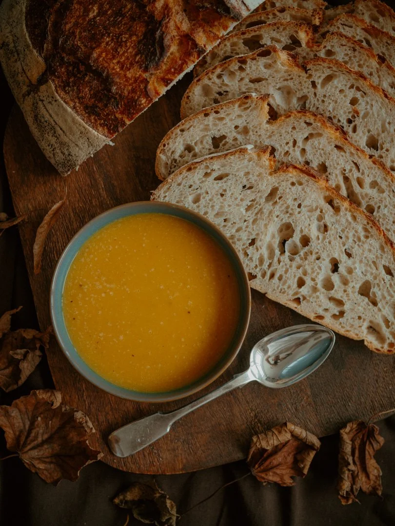 Overhead view of spiced squash soup served with slices of freshly baked sourdough bread.