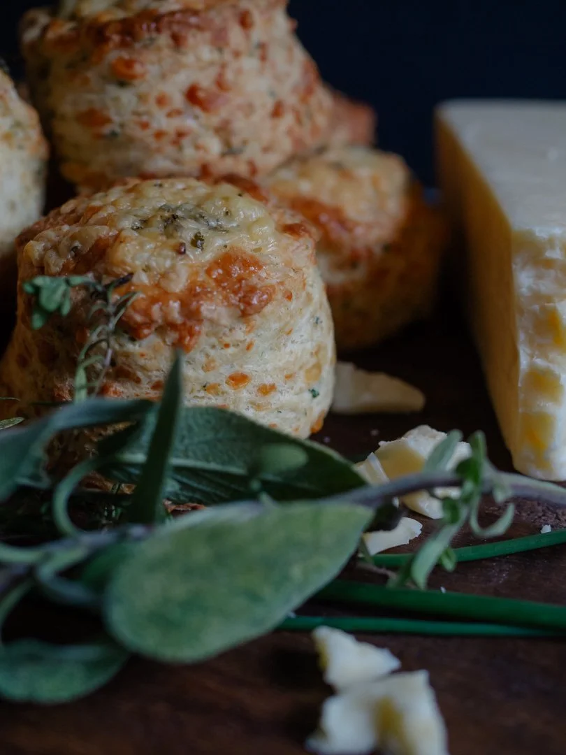 Homemade cheese and herb scones with fresh sage on a rustic table.