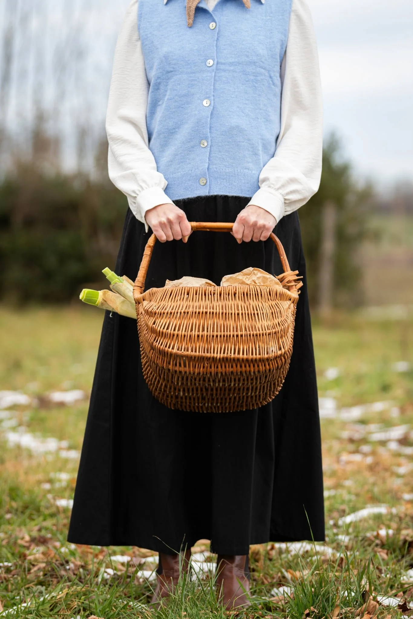Floriane of The Quiet Days holding a basket of fresh seasonal vegetables outdoors in the French countryside.