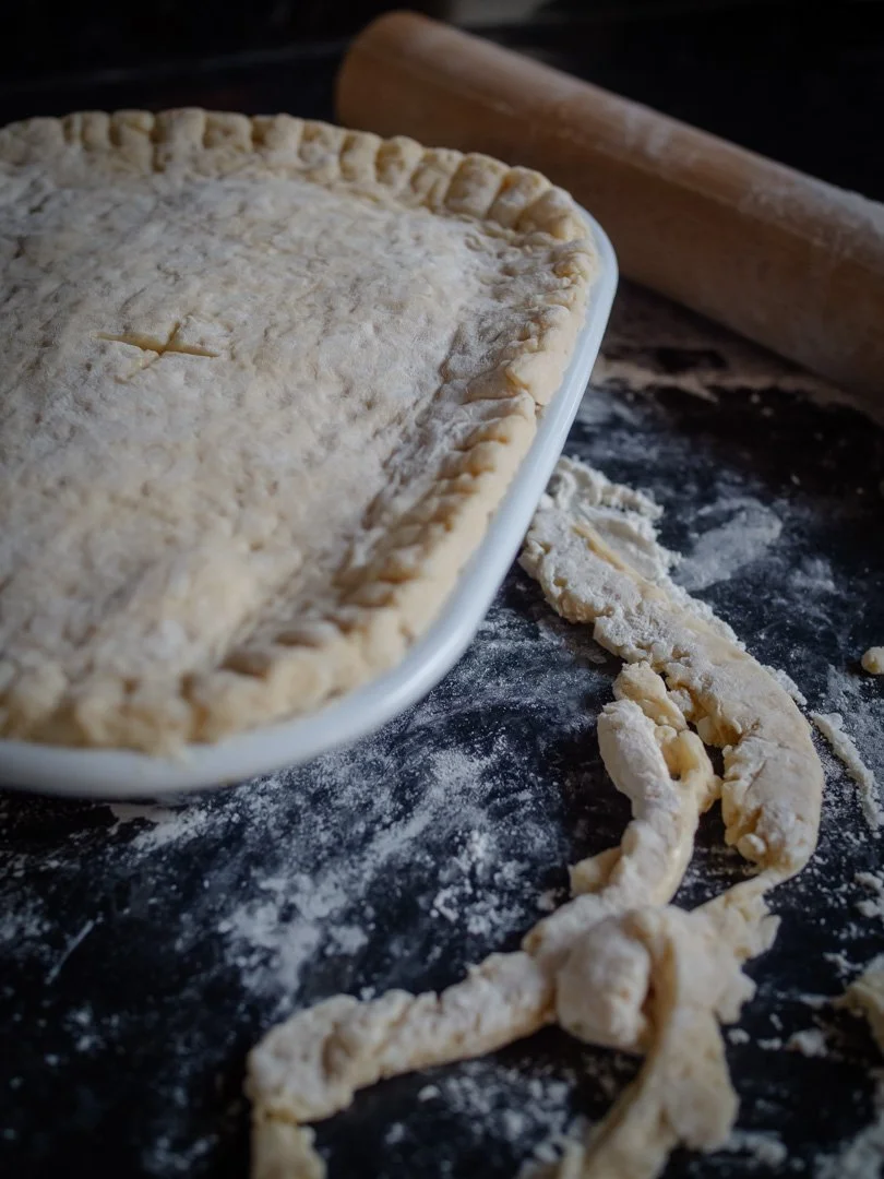 Close-up of hand-trimmed pastry on an uncooked pie, reflecting traditional home cooking and simple food.