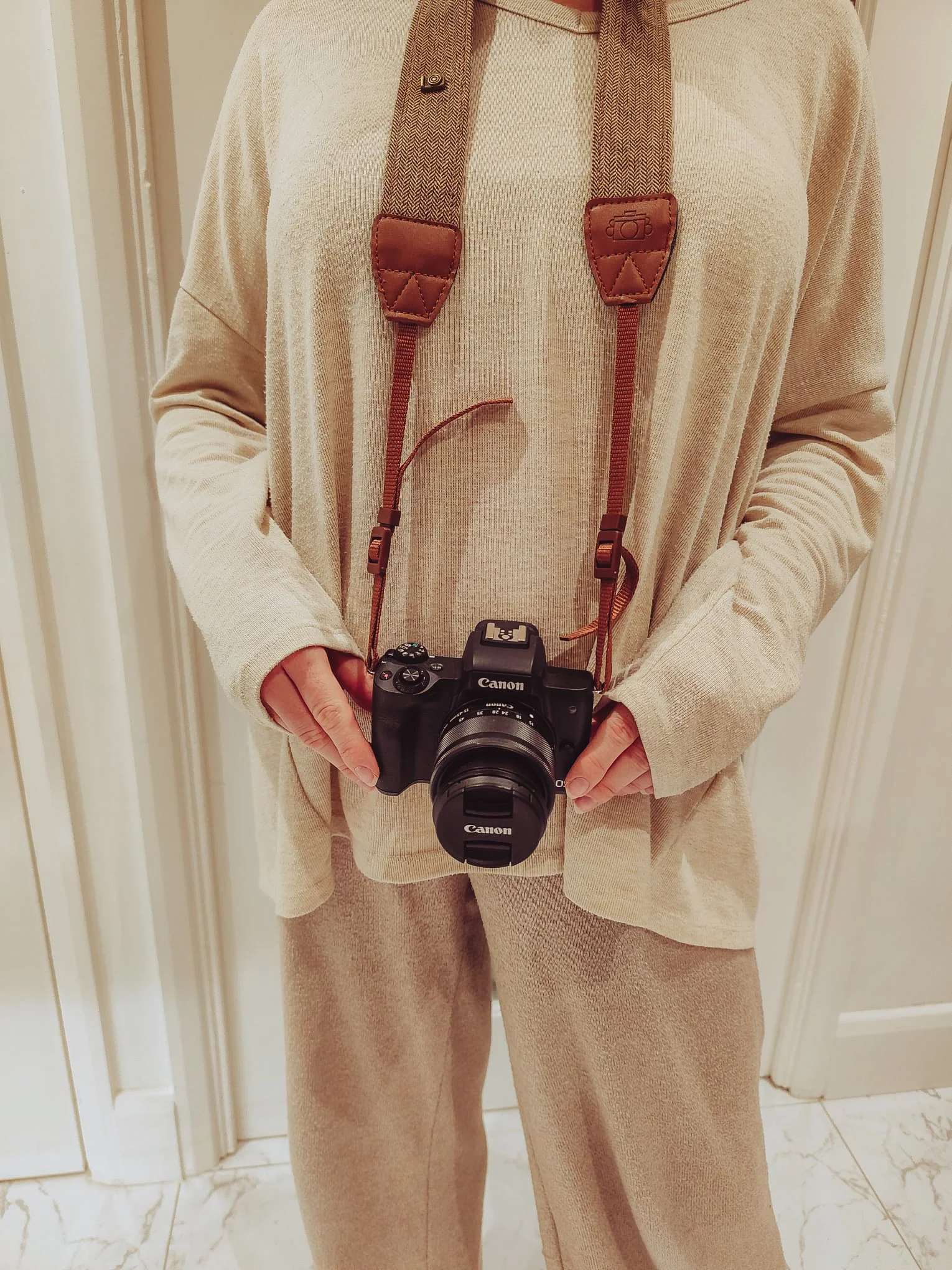 Shelley of Slow Bliss Studio standing indoors with camera around her neck, slow living photographer at work