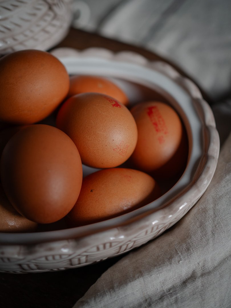 Ceramic chicken egg holder filled with fresh eggs in a traditional kitchen.