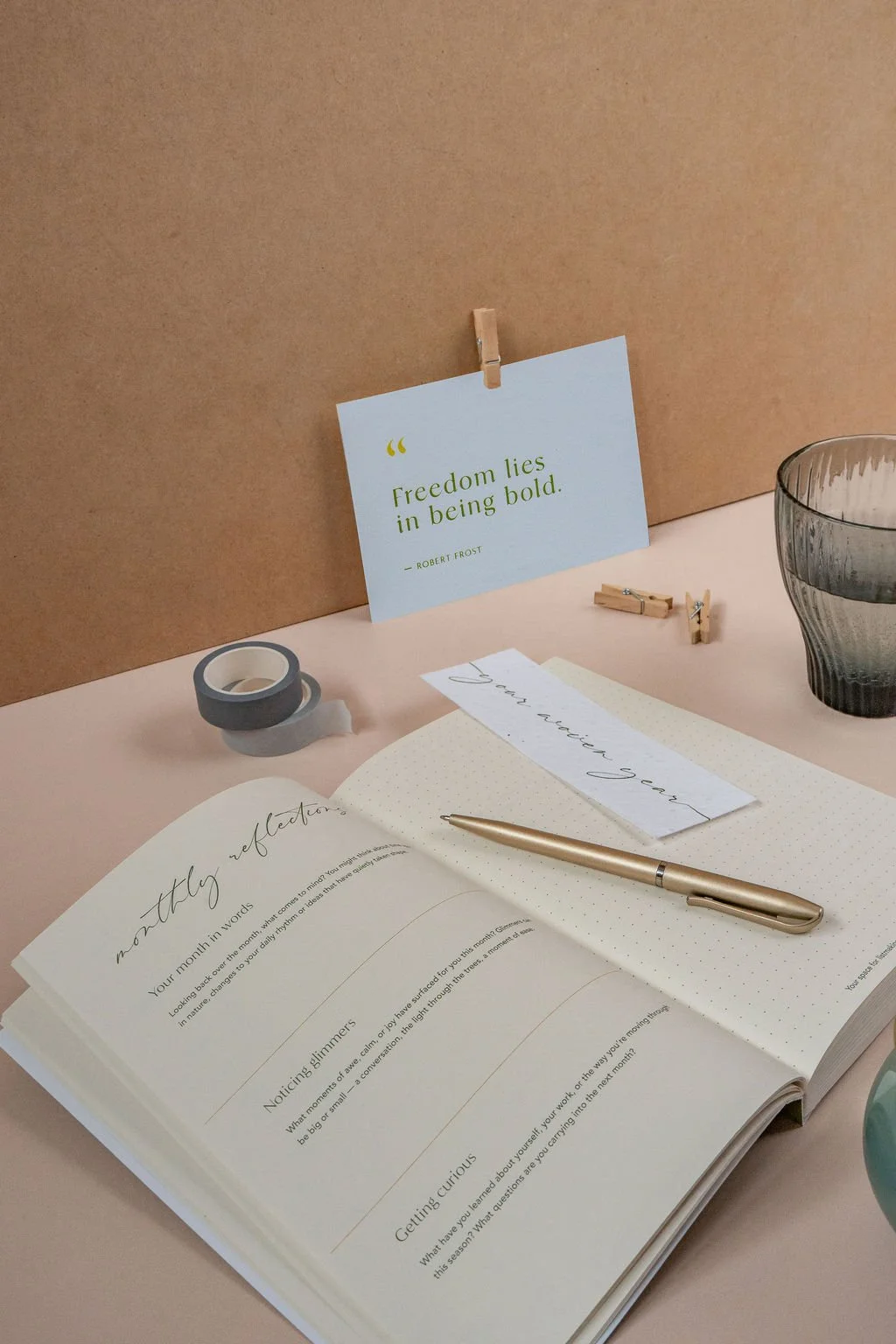 The Woven Year planner open on a desk with a pen and glass of water, inviting slow, seasonal reflection in professional life.