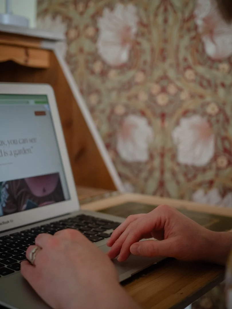 Clementine Rose working at a laptop on a wooden desk, reflecting a calm and intentional approach to work