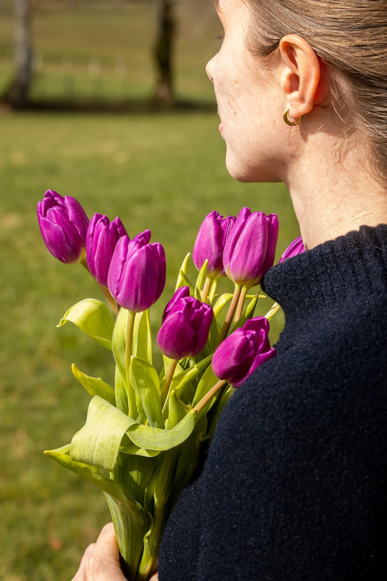 Floriane of The Quiet Days holding purple tulips outdoors in spring sunshine as part of her slow living lifestyle.