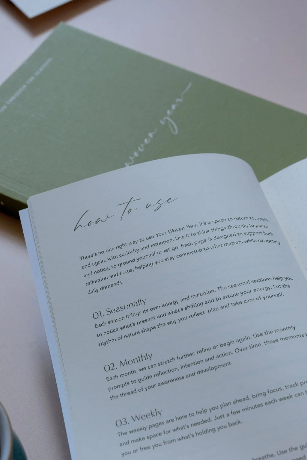 Open and closed copies of The Woven Year on a desk, designed as a gentle companion for seasonal reflection throughout the year.