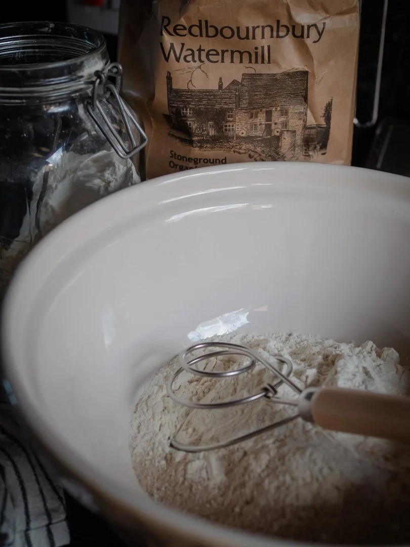 Close-up of flour, salt and yeast before mixing, highlighting the textures of stoneground flour in a slow living kitchen.