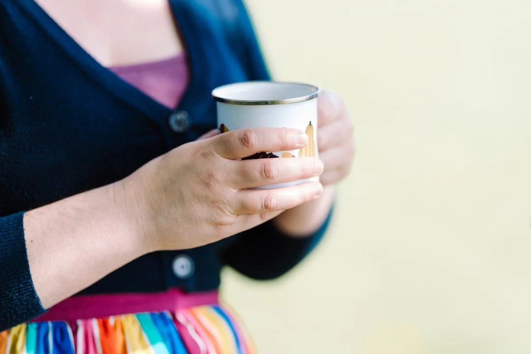 Rhiannon Adler holding an enamel mug while enjoying a quiet moment outdoors.