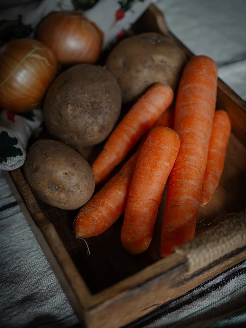 Wooden tray with onions, potatoes and carrots, simple traditional kitchen ingredients.