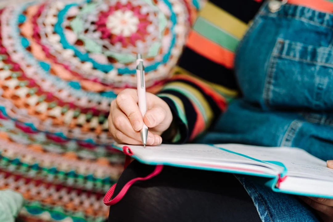 Rhiannon Adler writing in a notebook, reflecting a thoughtful and creative approach to slow living.