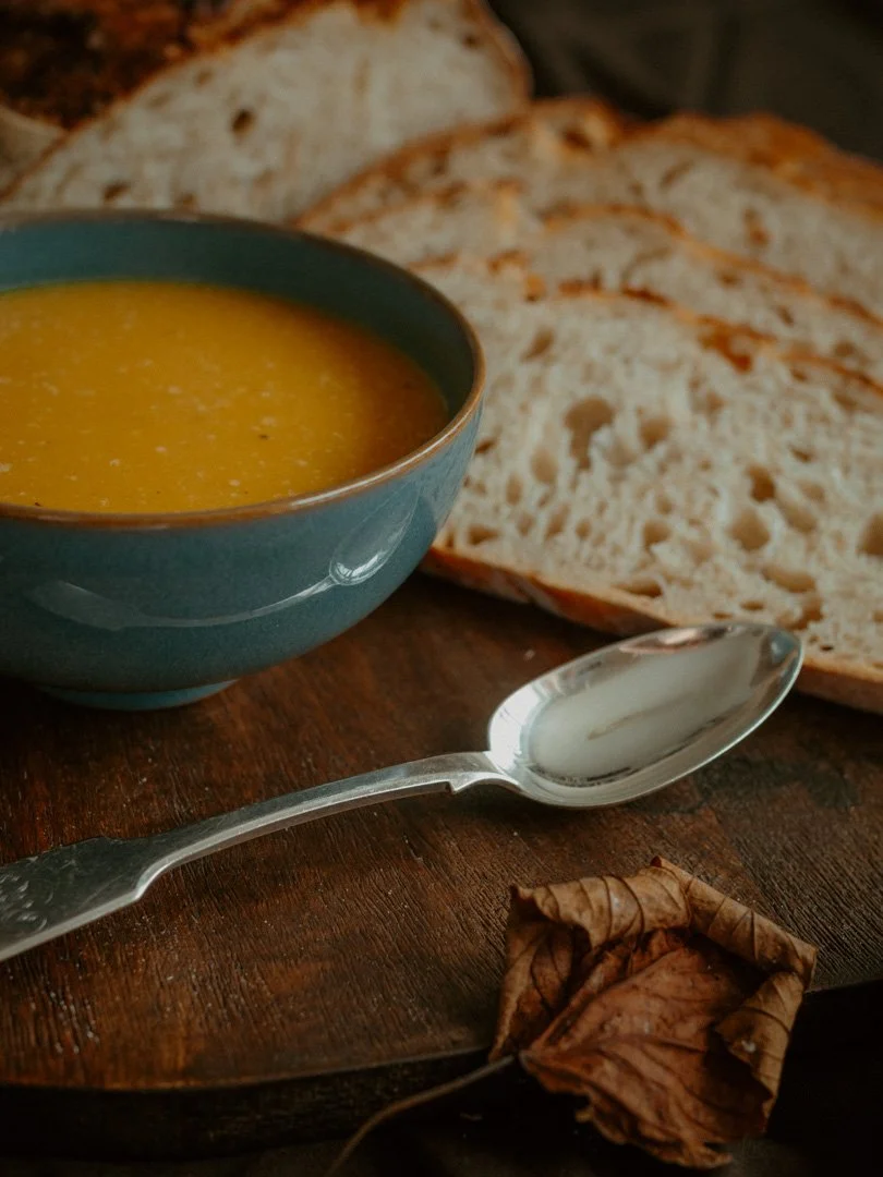 Close-up of a bowl of spiced squash soup with freshly baked sourdough bread alongside.