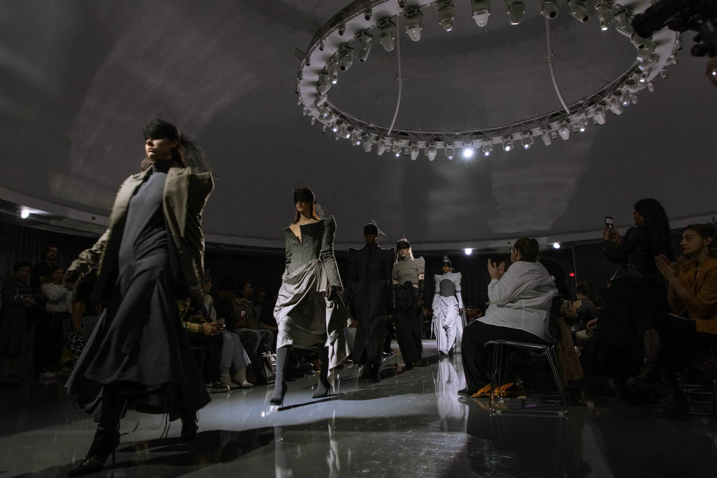 Models walking in a line wearing grey outfits at the GM Design Dome during the annual CCS Fashion Design Runway Show