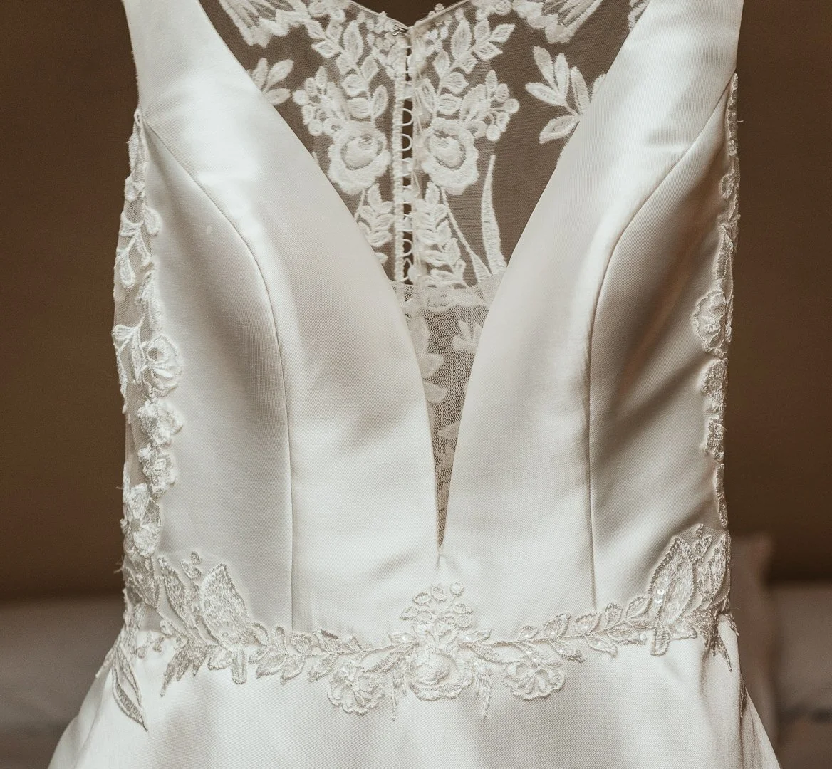 Close-up of a wedding dress with lace details and a plunging neckline.