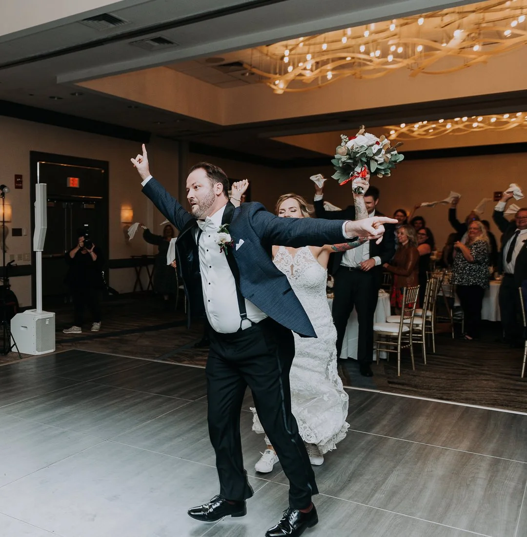 Bride and groom dancing at their wedding reception, surrounded by guests.