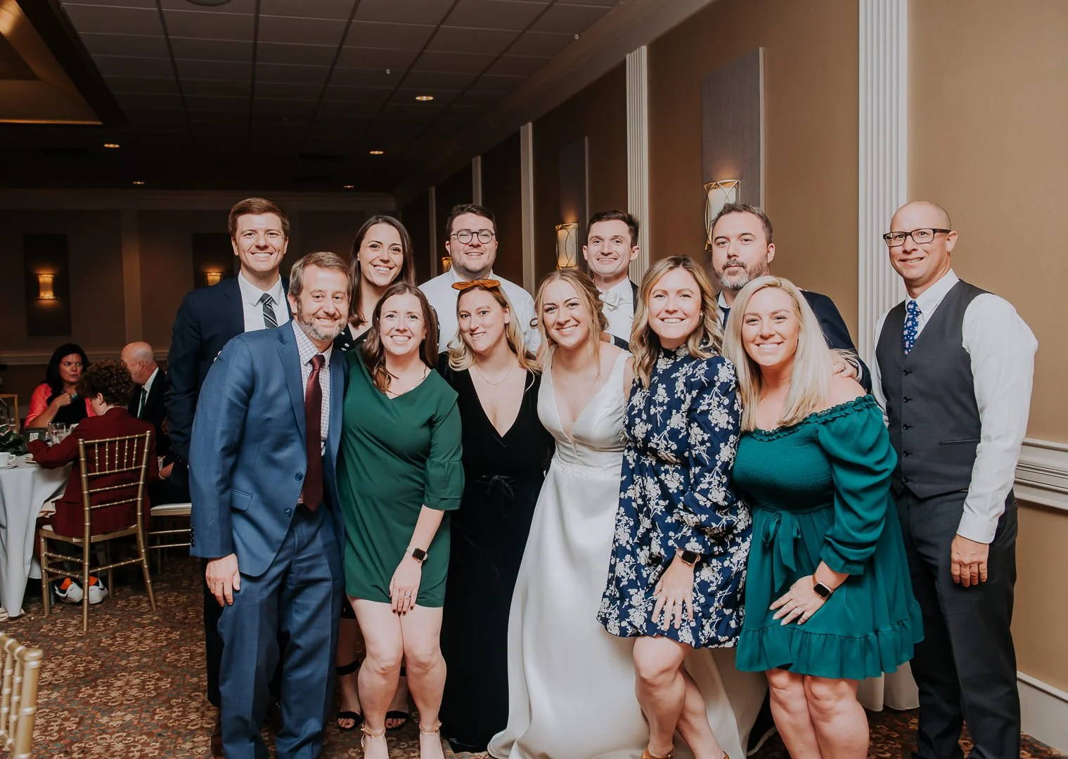 Group of people dressed in formal attire posing for a photo at an indoor event.