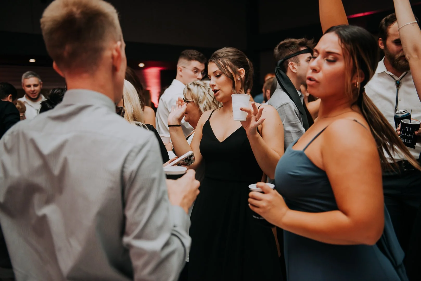 People dancing and socializing at a party in a dimly lit venue.