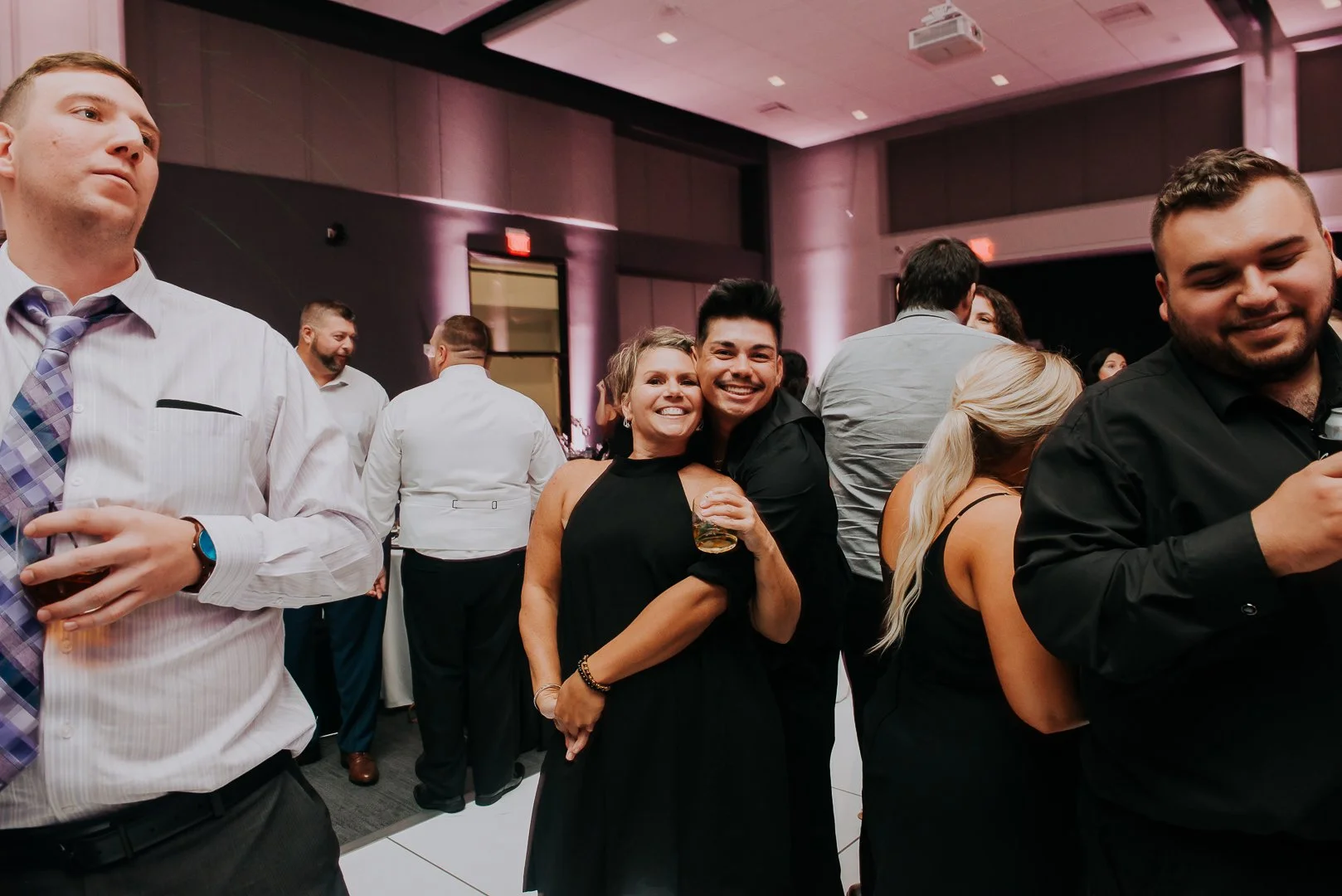 People dancing and socializing at a party or celebration in a dimly lit indoor venue.