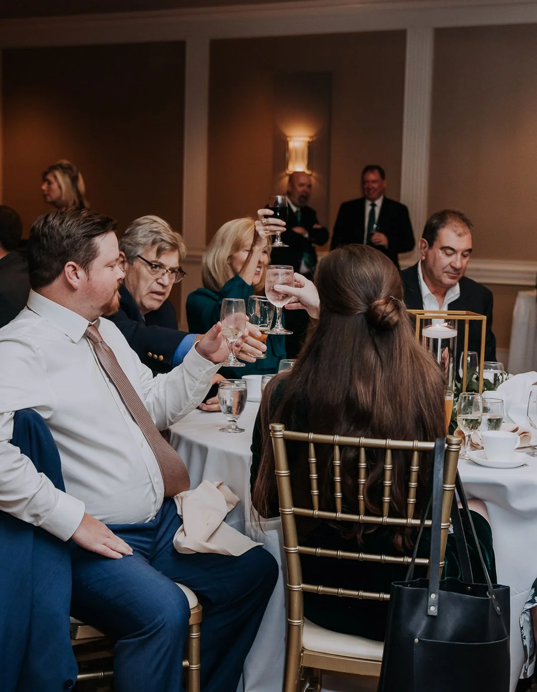 People sitting at a banquet table raising glasses in a toast at a formal event.