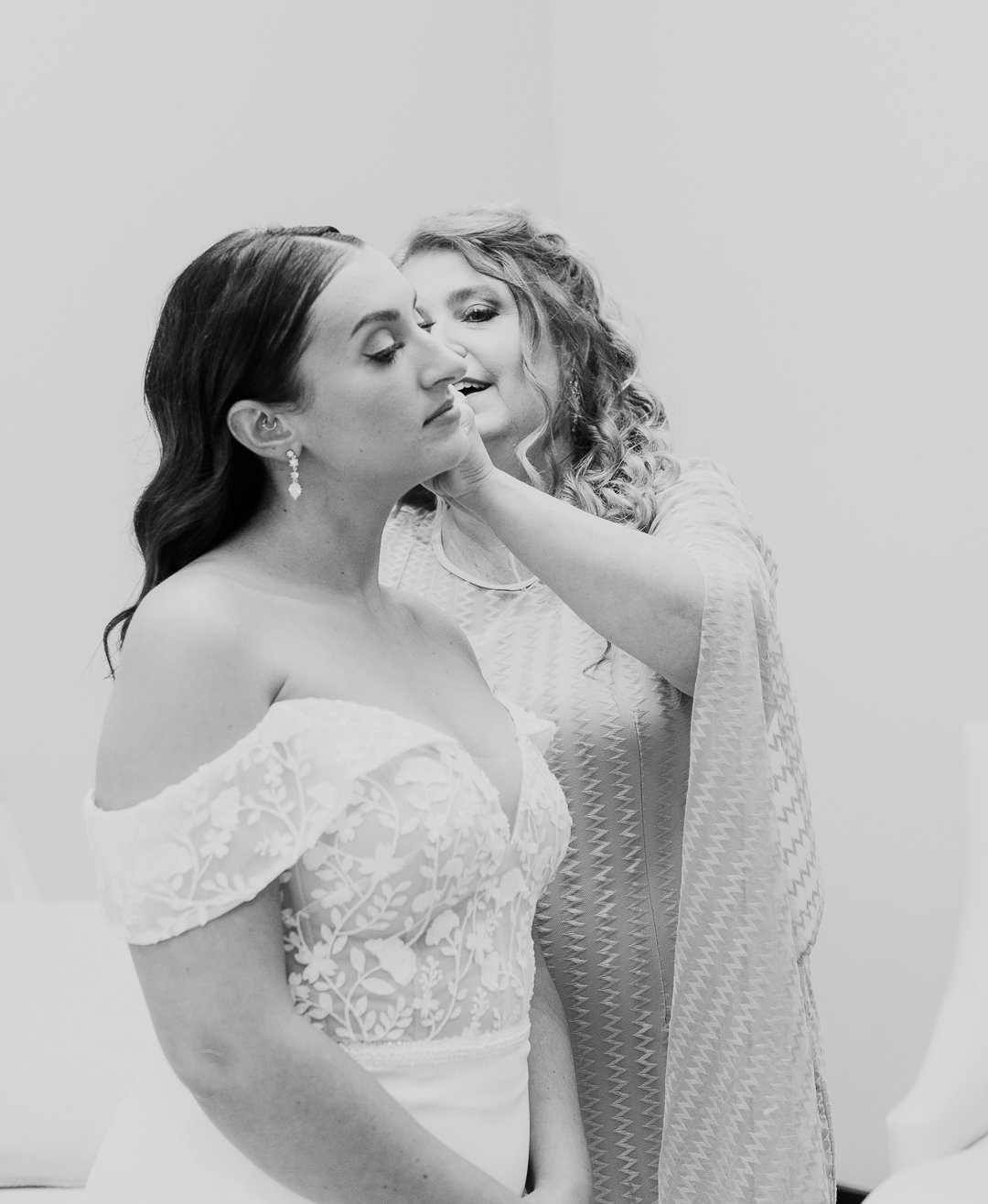 A woman getting her makeup applied in a behind-the-scenes setting, with another woman assisting her.