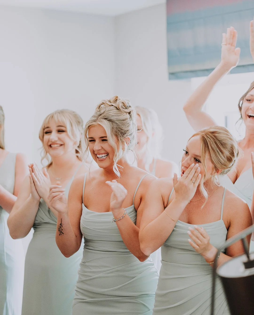 Bridesmaids in light gray dresses smiling and laughing at a wedding
