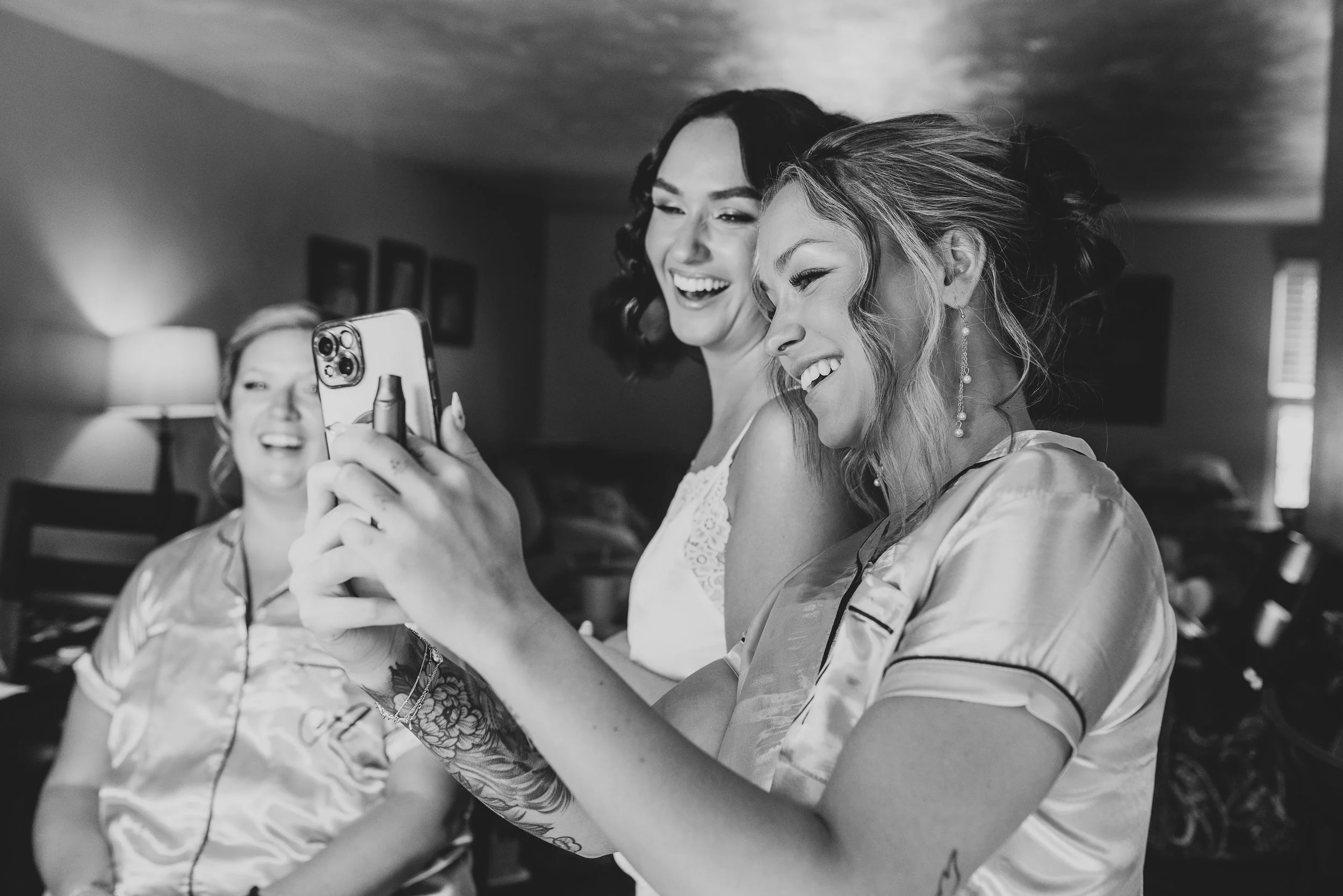 Three women sharing a joyful moment, taking a selfie together in a cozy indoor setting.