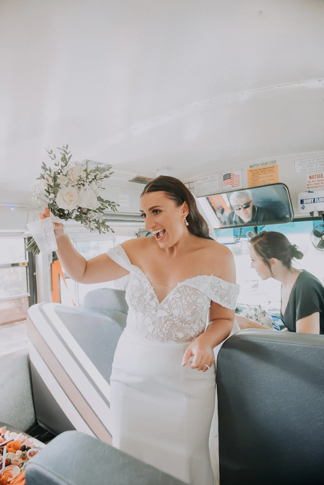 A woman in a wedding dress holding a bouquet of flowers on a bus.