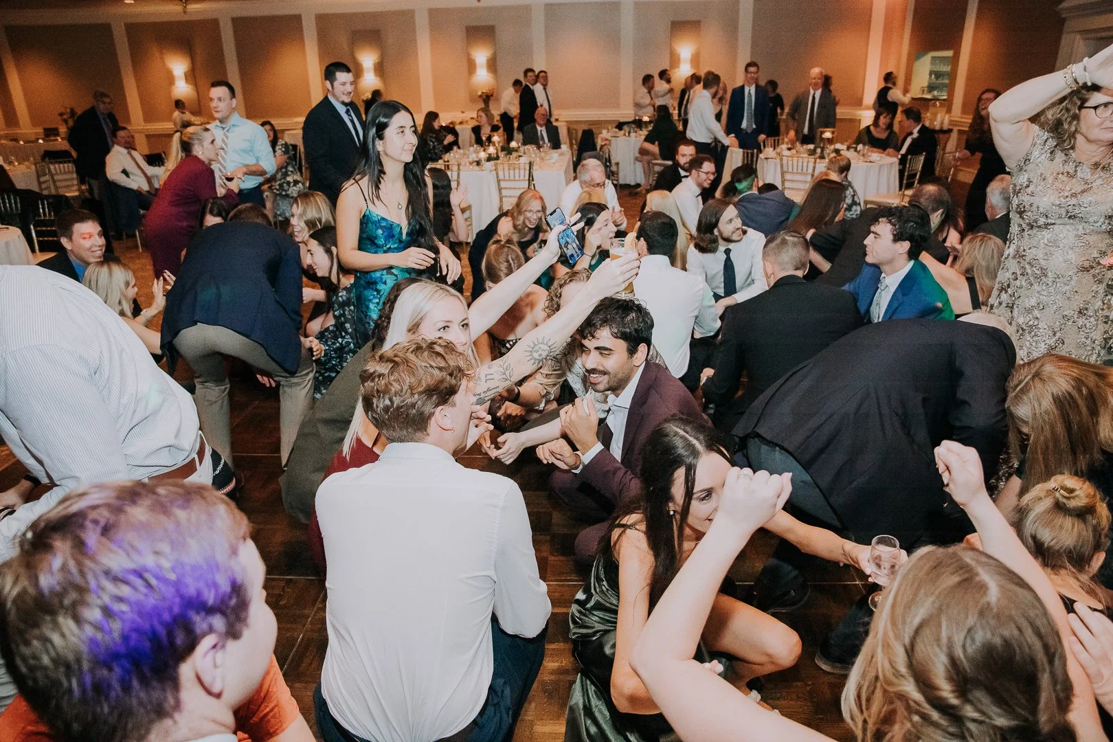 Crowd of people dancing and socializing at a formal event or wedding reception in a banquet hall