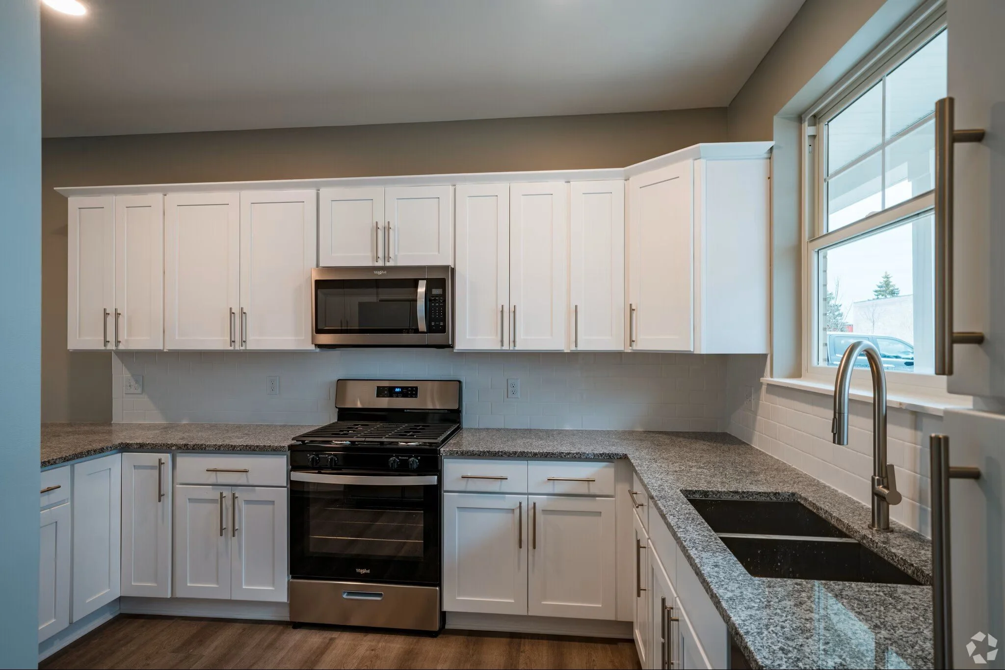 apartment kitchen with white cabinets, granite counter top, stainless steel appliances
