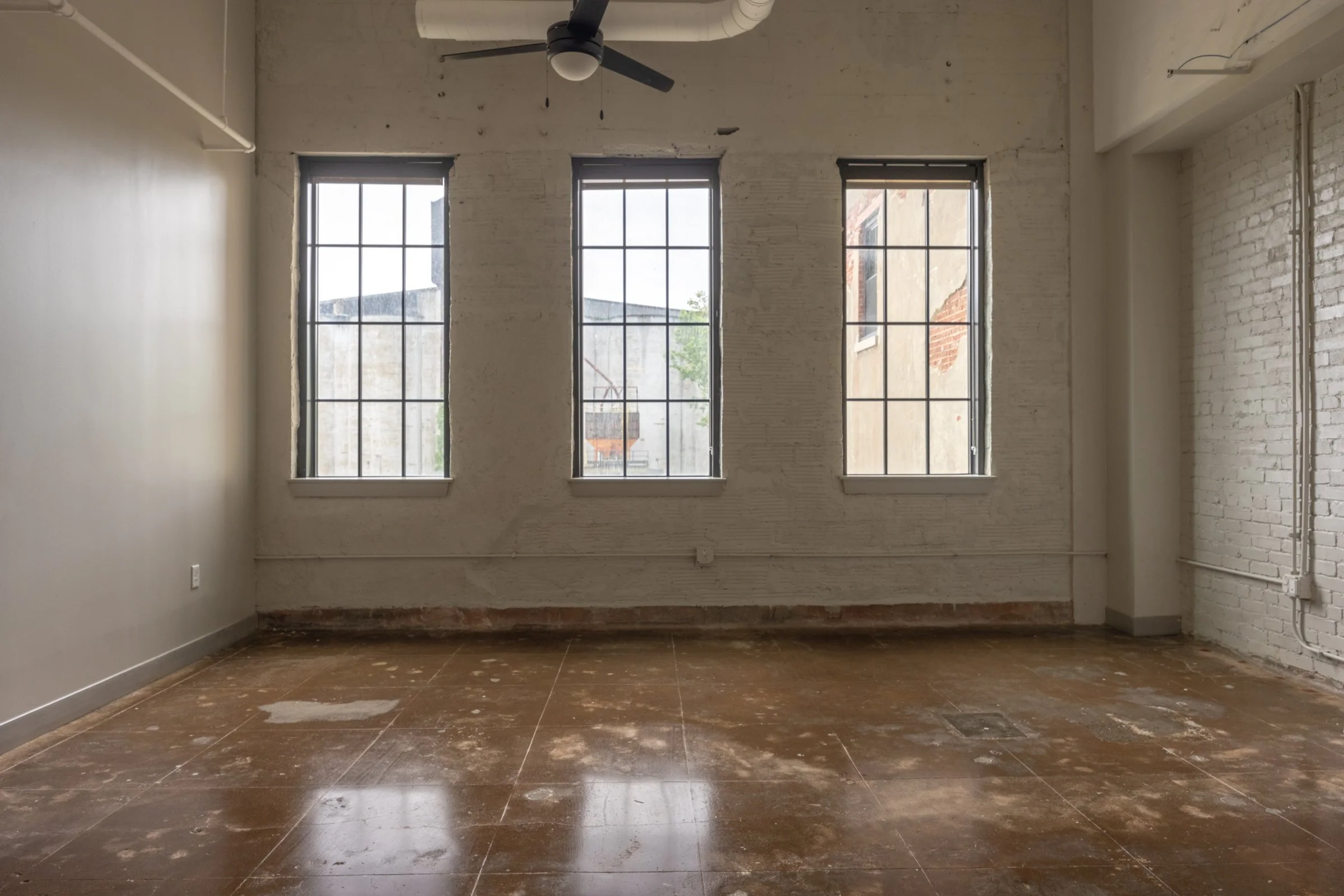 Empty room in restored malthouse apartments, white brick wall and mosaic floors