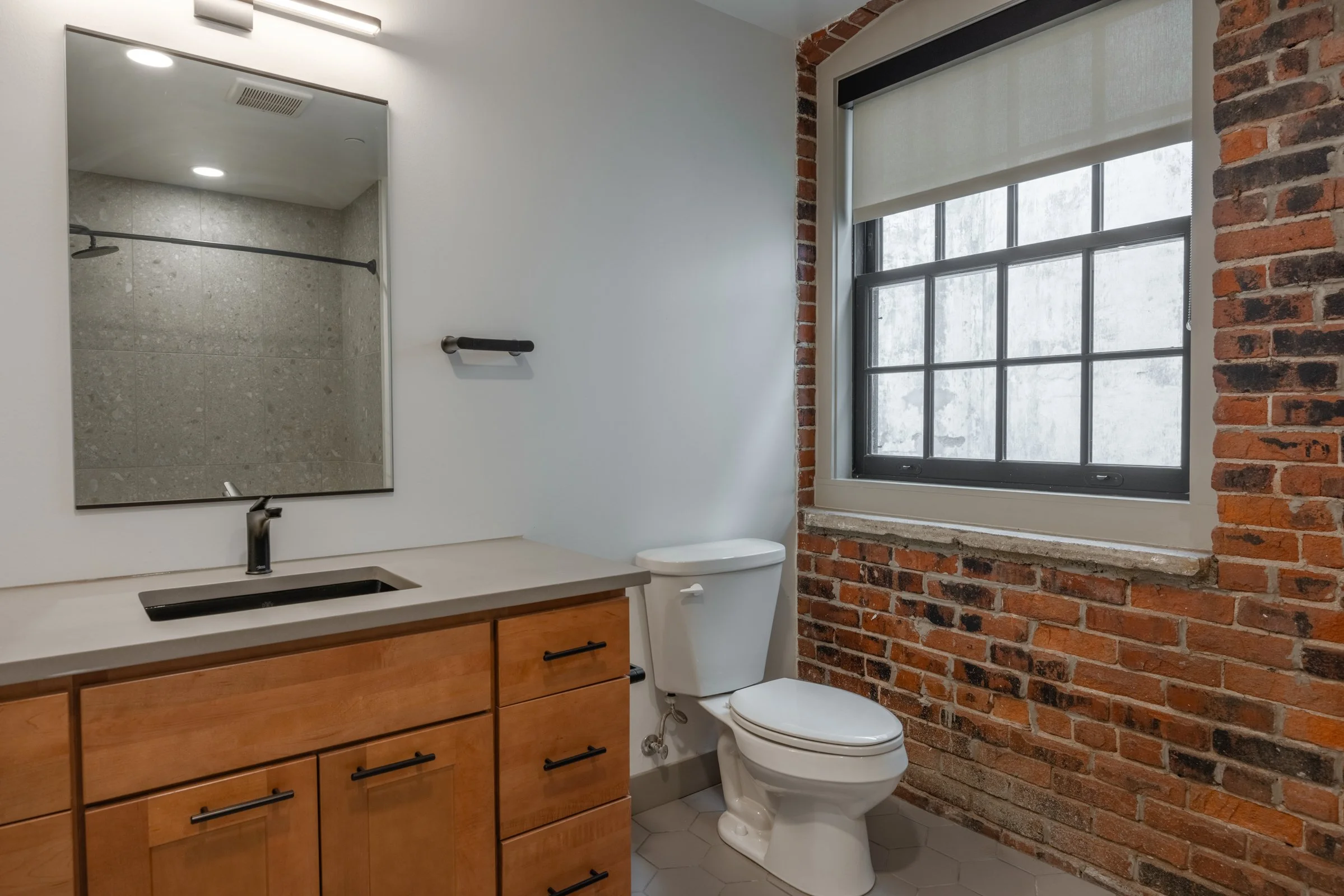 Apartment bathroom with brick wall and gray counters