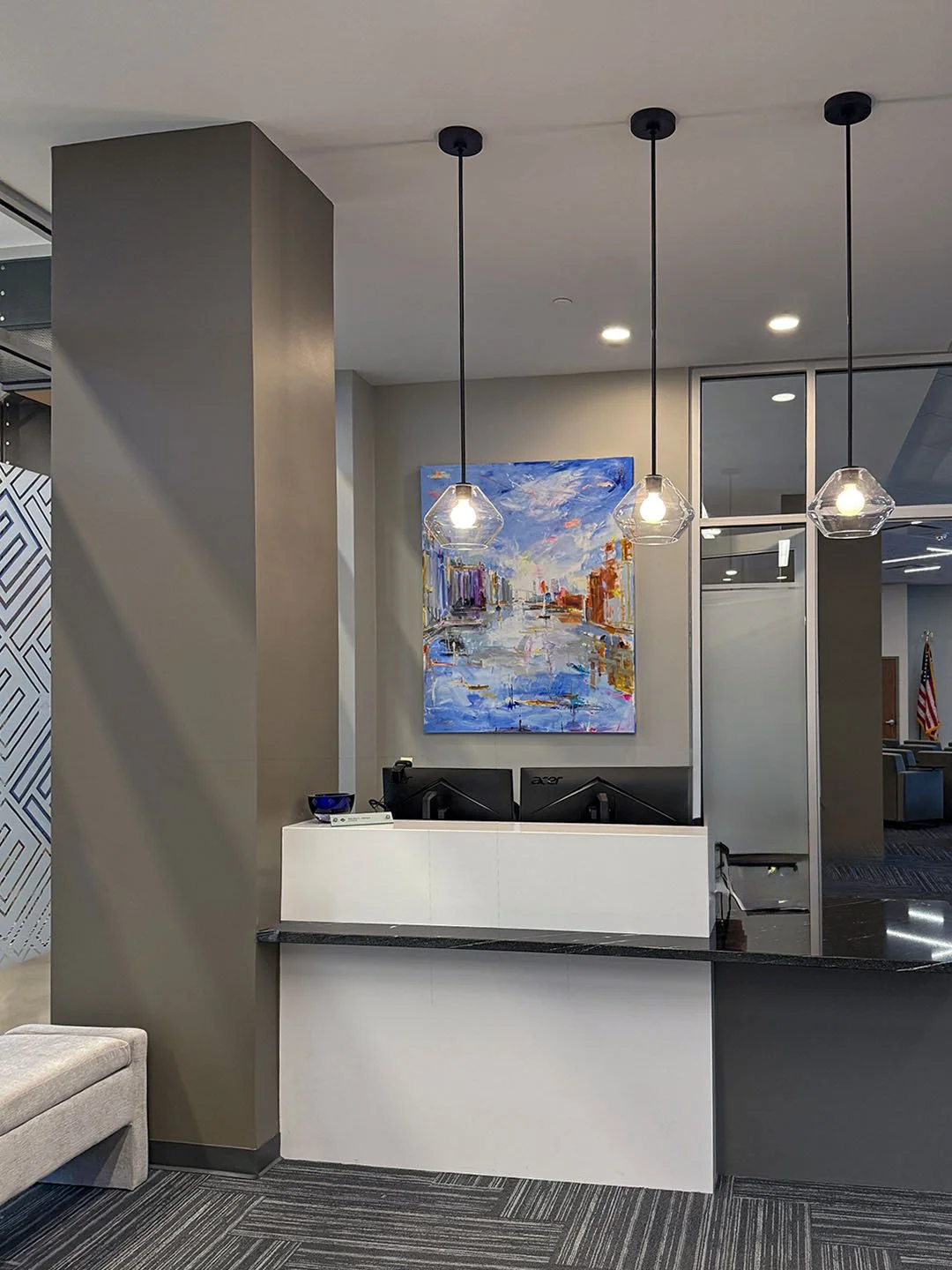 Front desk area of Lippes Mathias with artwork and pendant lights hanging down