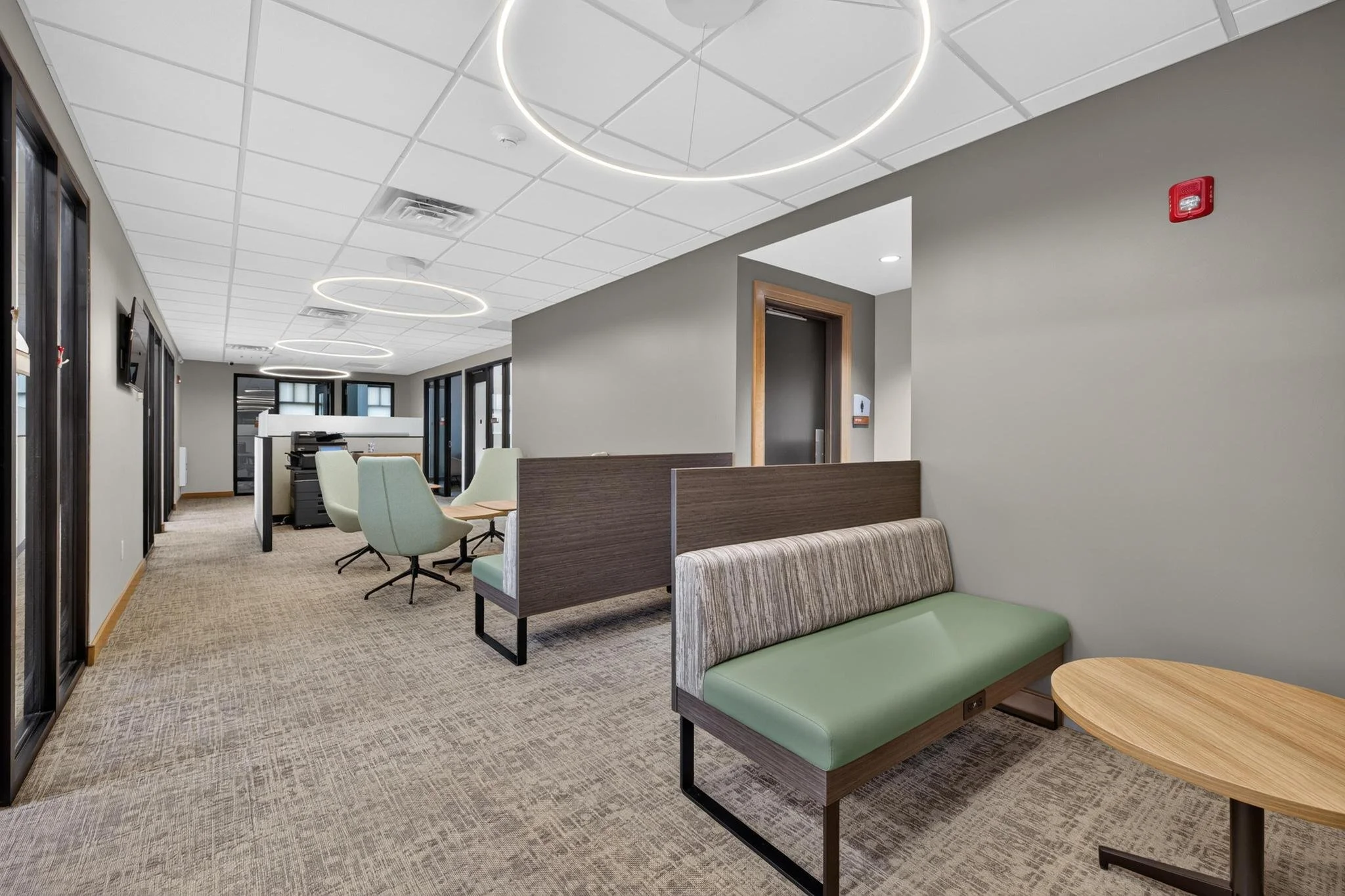 modern office workspaces with circular overhead light fixtures and green couches