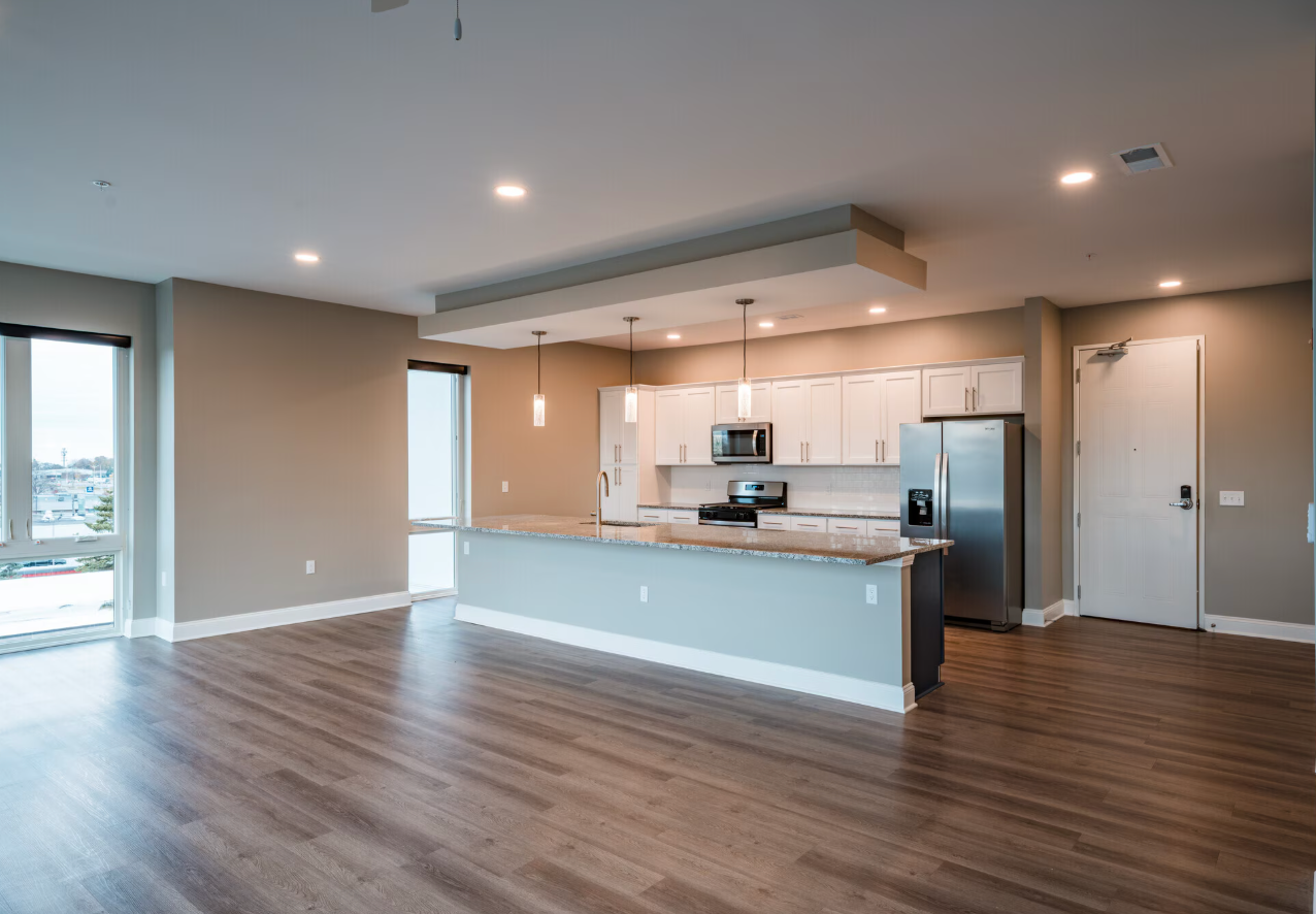 common area of the pointe apartments with hardwood floors, granite counter tops, stainless steel appliances and pendent lights hanging above the island