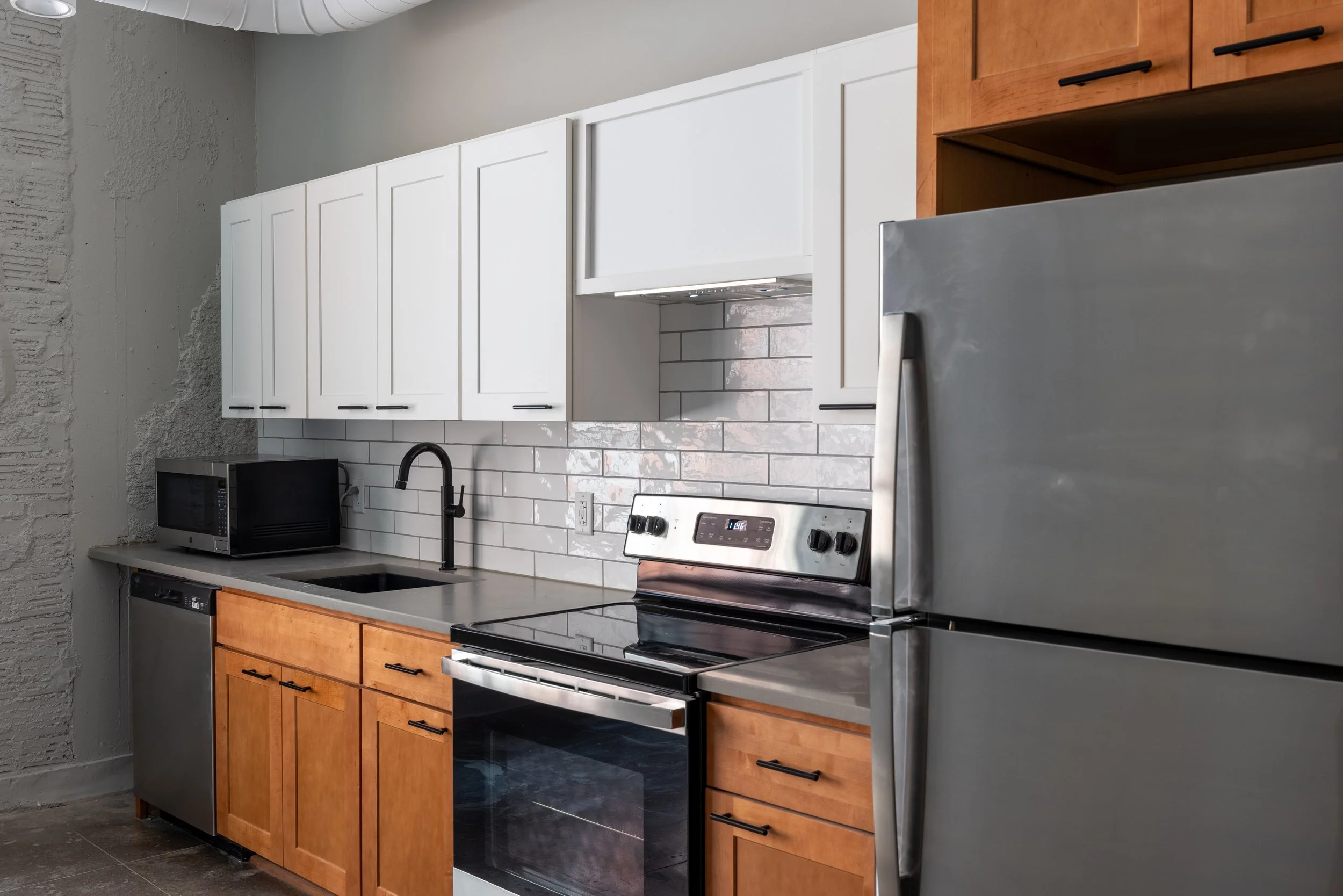 apartment kitchen with white tiled backsplash and gray counters